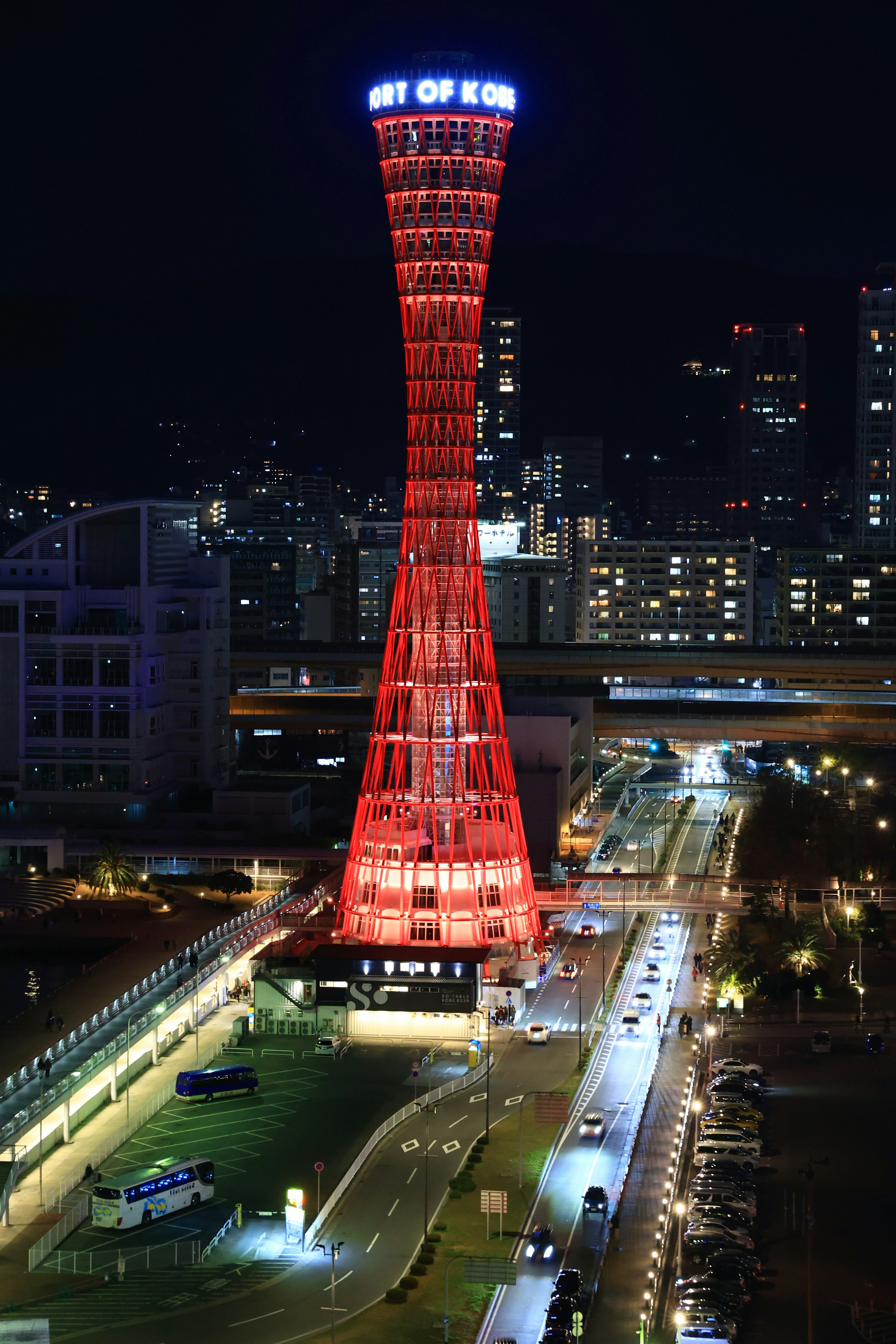 Torre de Kobe de noche iluminada en rojo con el horizonte de la ciudad