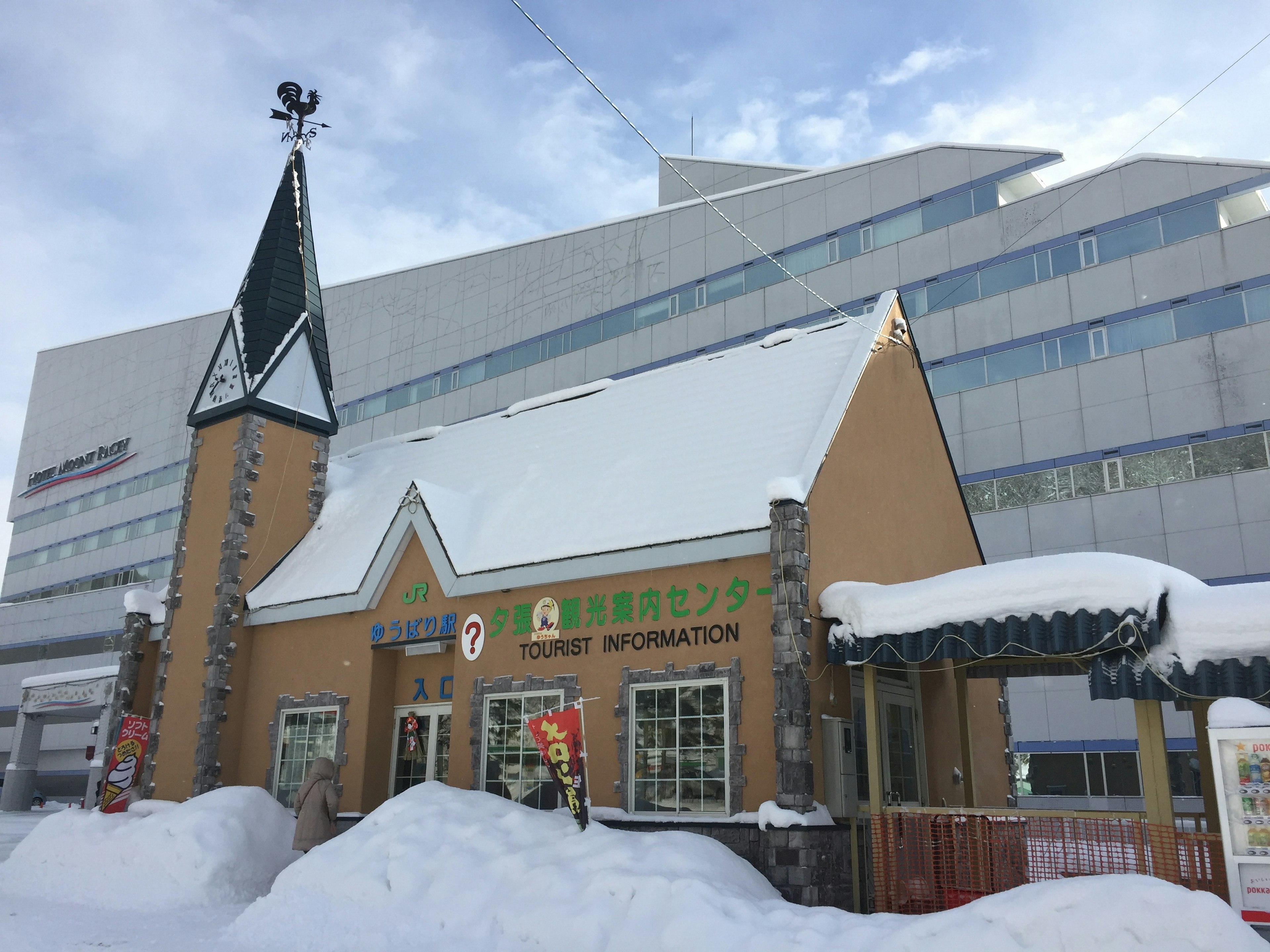 Bâtiment traditionnel recouvert de neige avec une structure moderne en arrière-plan