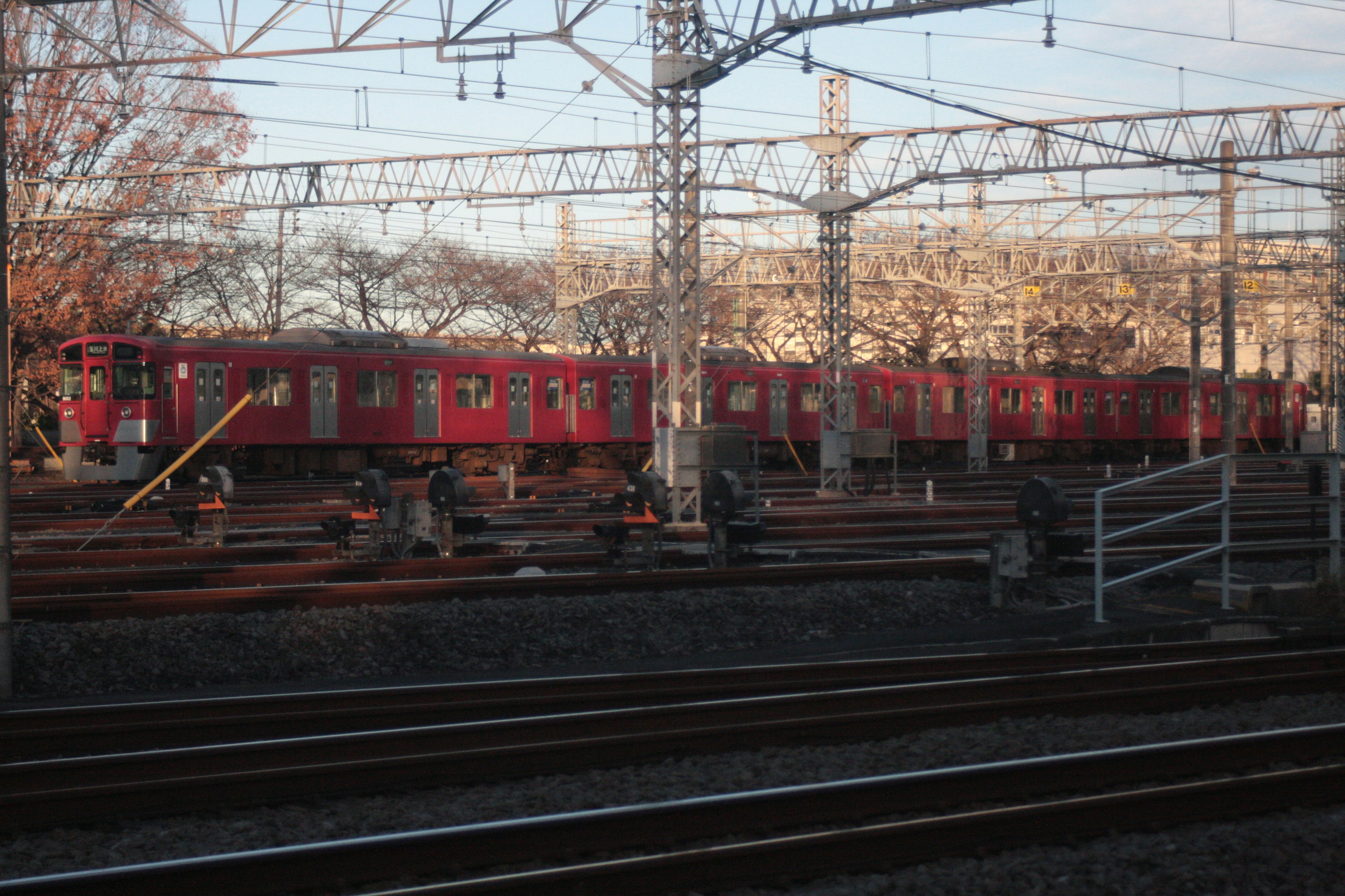 รถไฟแดงจอดอยู่บนรางพร้อมสายไฟฟ้าเหนือศีรษะ