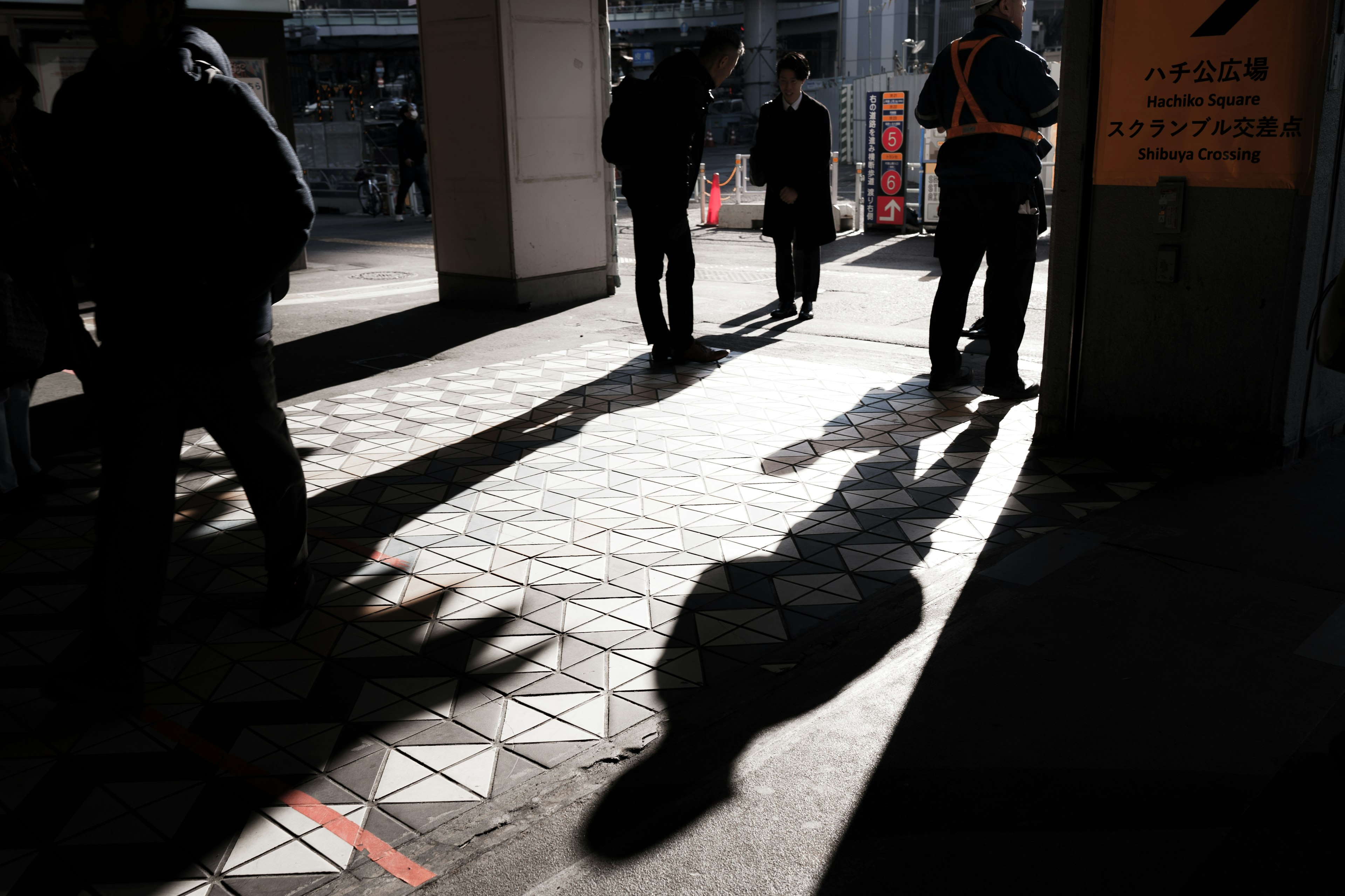 人々が影を作りながら歩く都市の風景