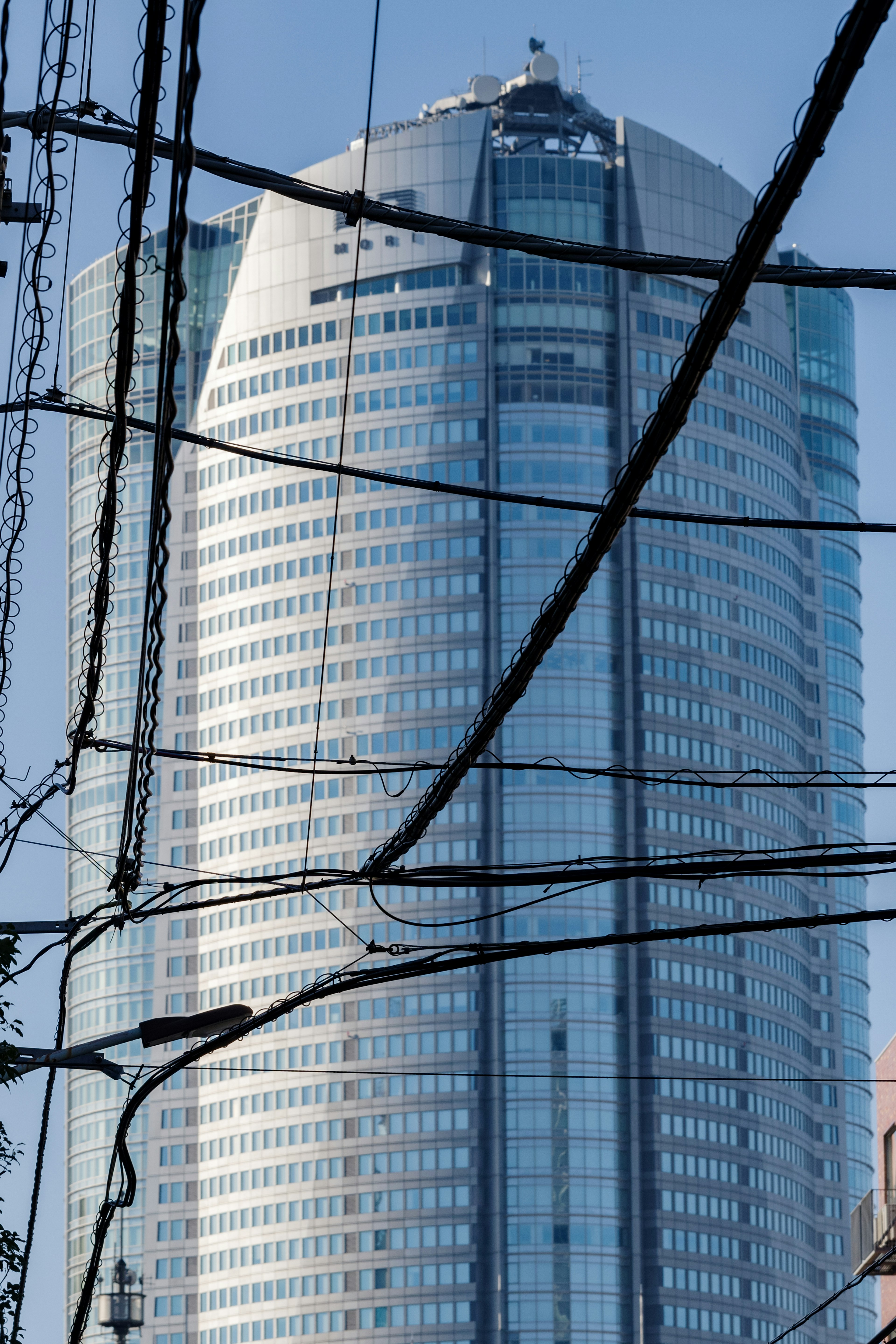 Wolkenkratzer mit Glasfassade, die von Stromleitungen durchzogen wird