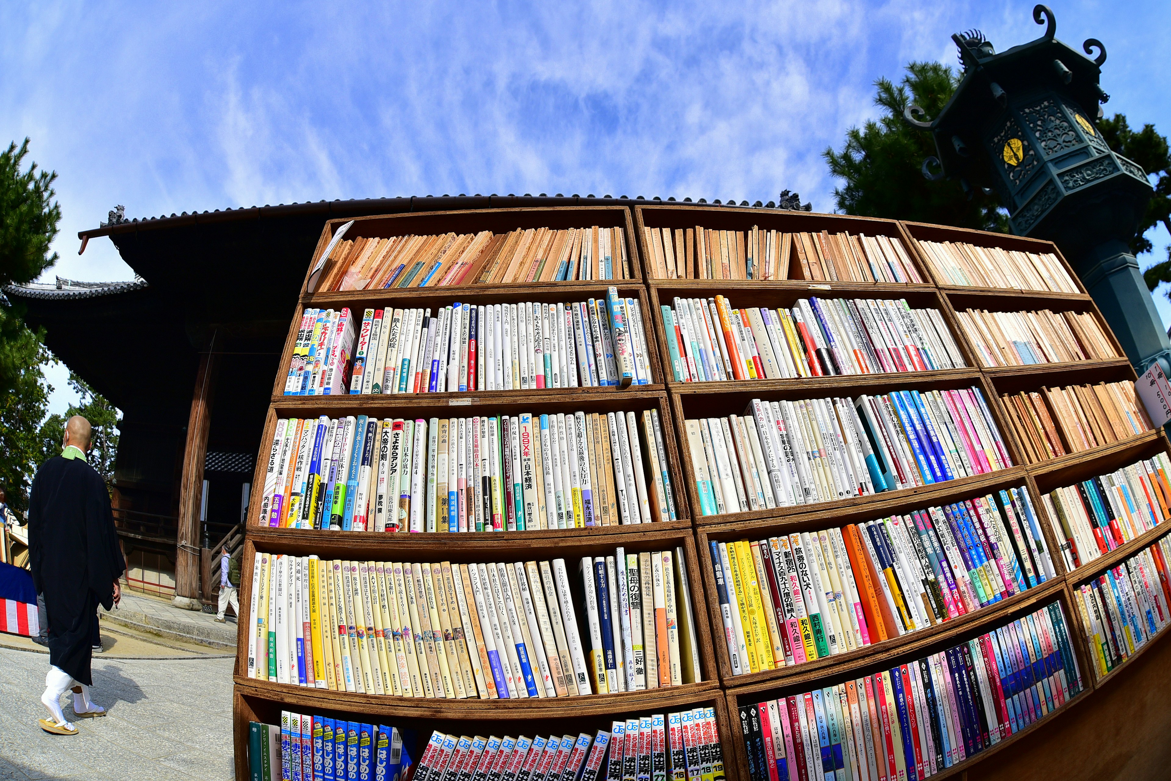 Wooden bookshelf filled with numerous books against a blue sky