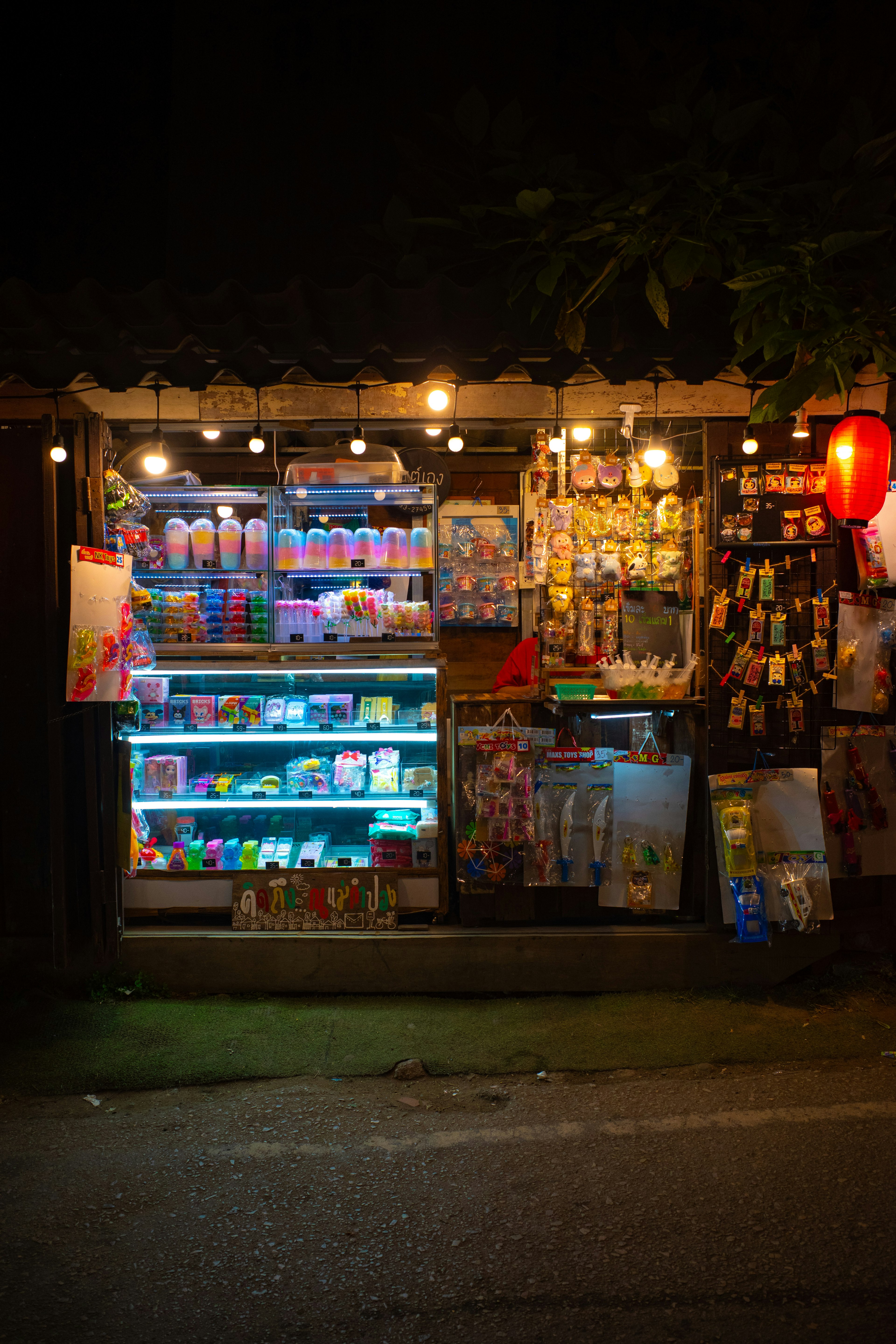 Produk berwarna-warni yang dipajang di stan pasar malam dengan lampu