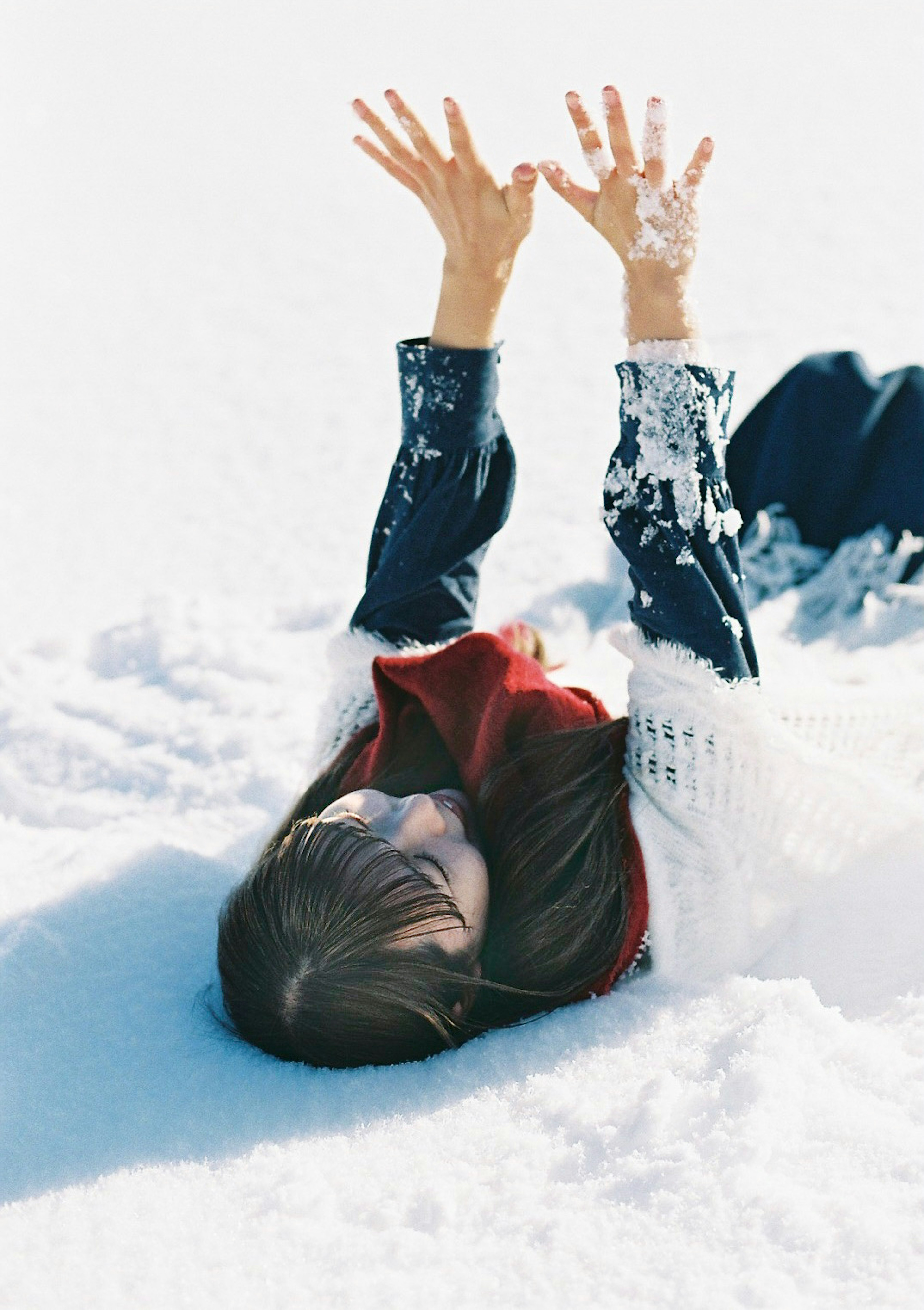 Mujer disfrutando en la nieve levantando las manos para sacudirse la nieve