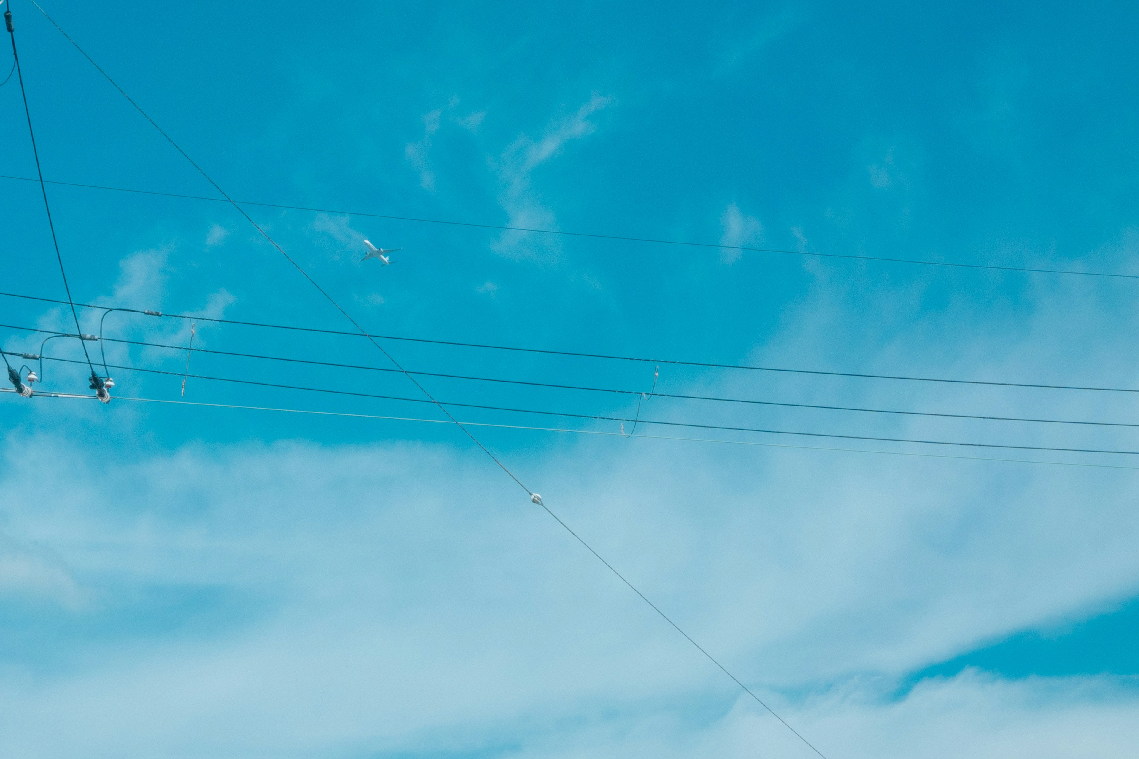 A clear blue sky with white clouds and visible power lines