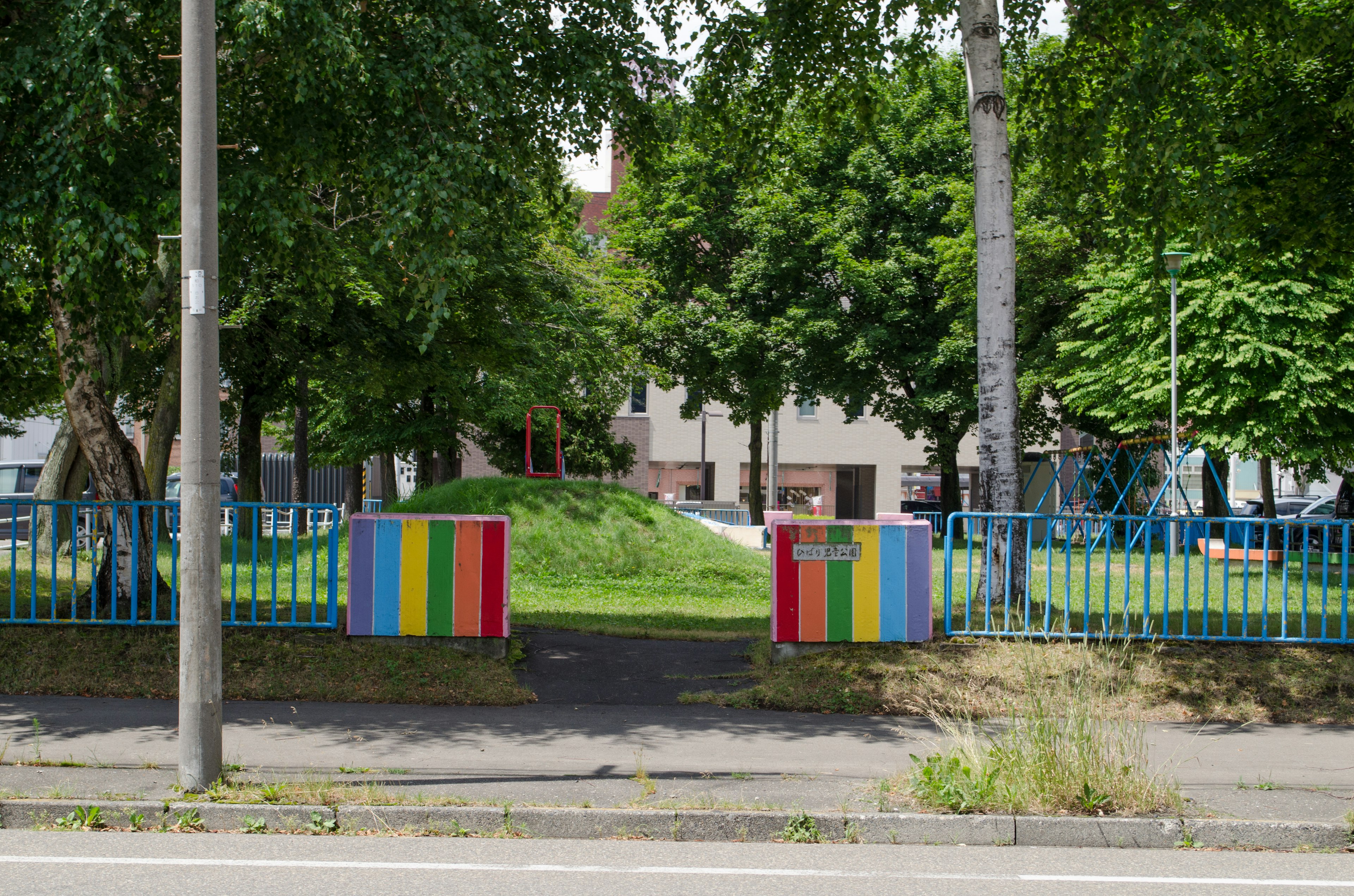 Entrée colorée d'un parc entouré d'arbres verts avec des équipements de jeu visibles