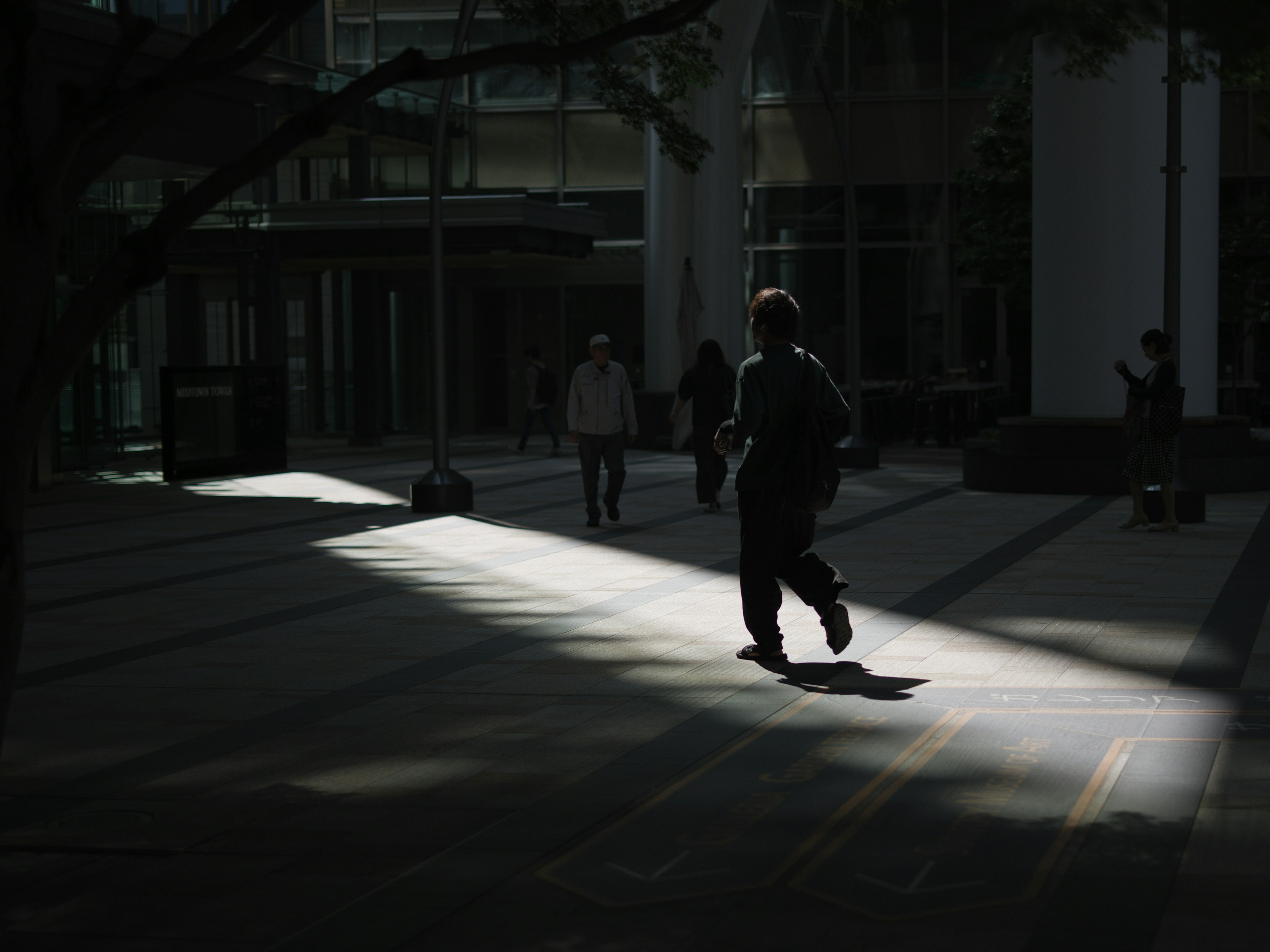 A silhouette of a person walking through a beam of light in a dimly lit area