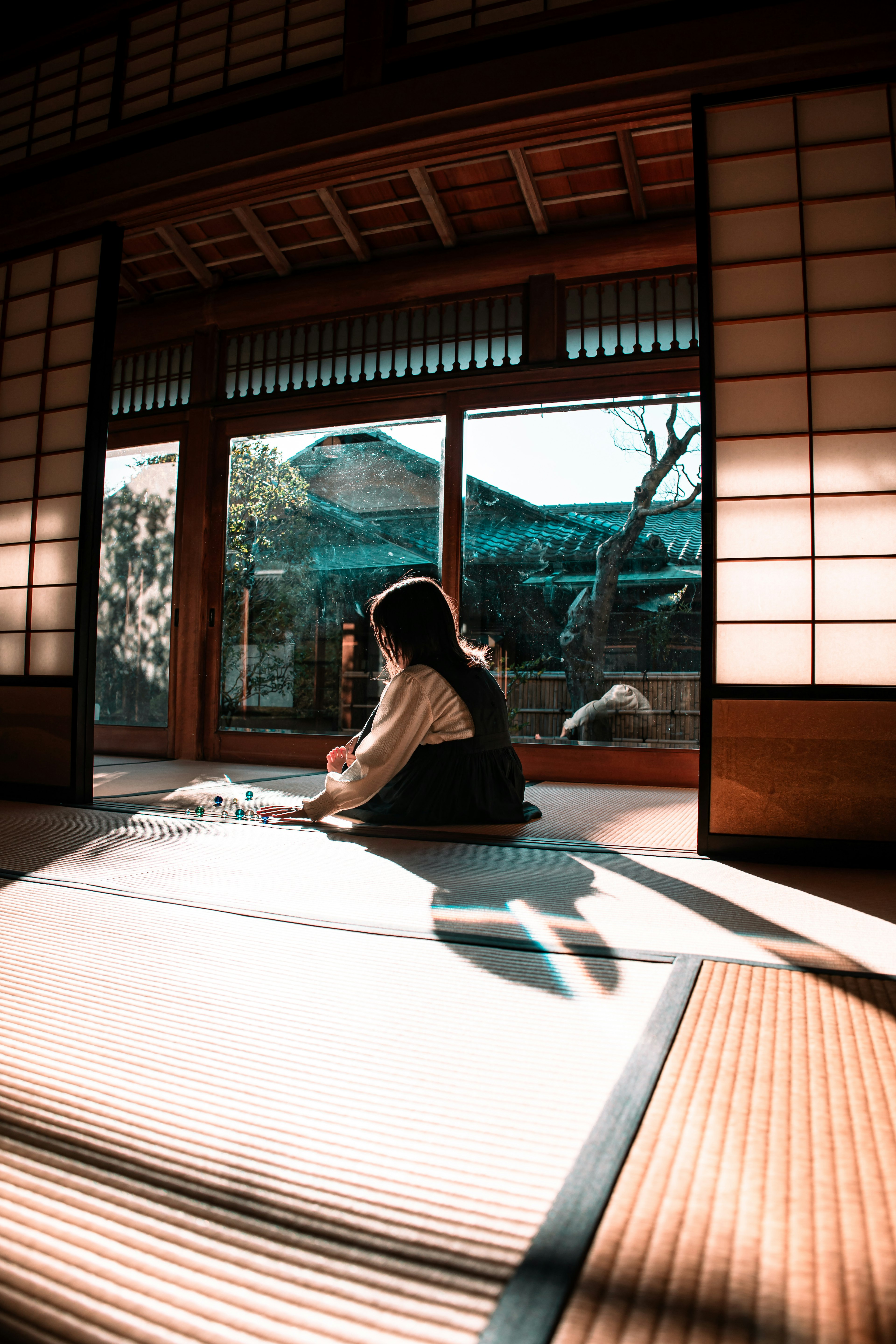 Siluet seorang wanita duduk di ruangan tradisional Jepang dengan cahaya alami yang masuk