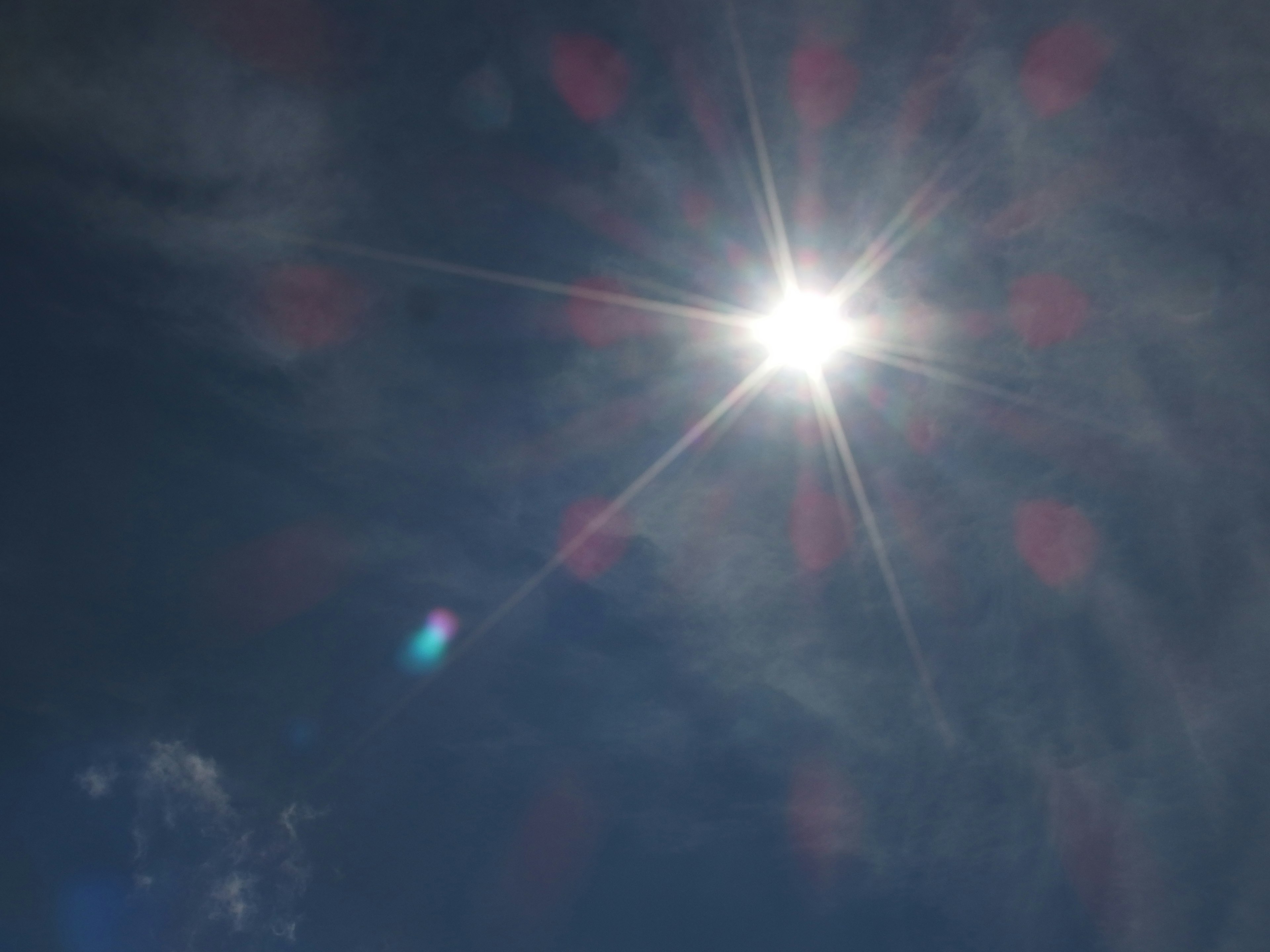 Bright sun shining in a clear blue sky with wispy clouds