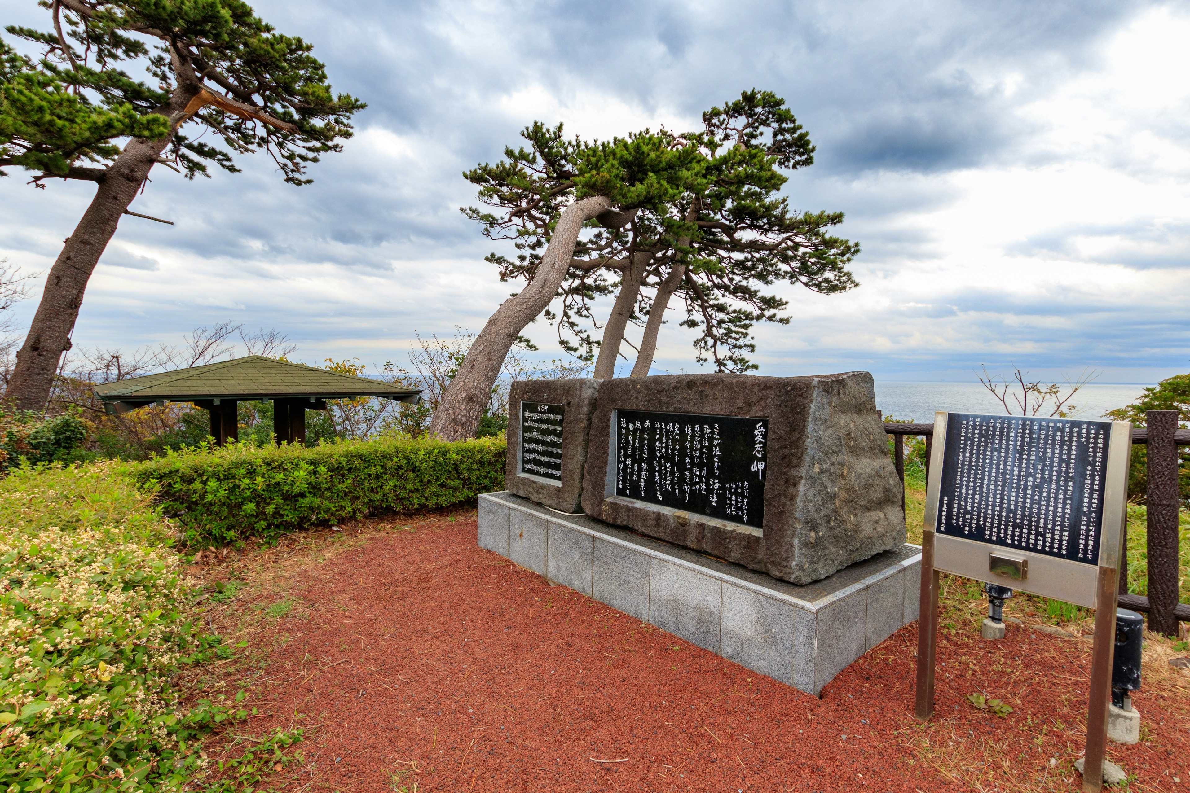 Vue pittoresque avec un grand monument en pierre et des panneaux d'information dans un parc