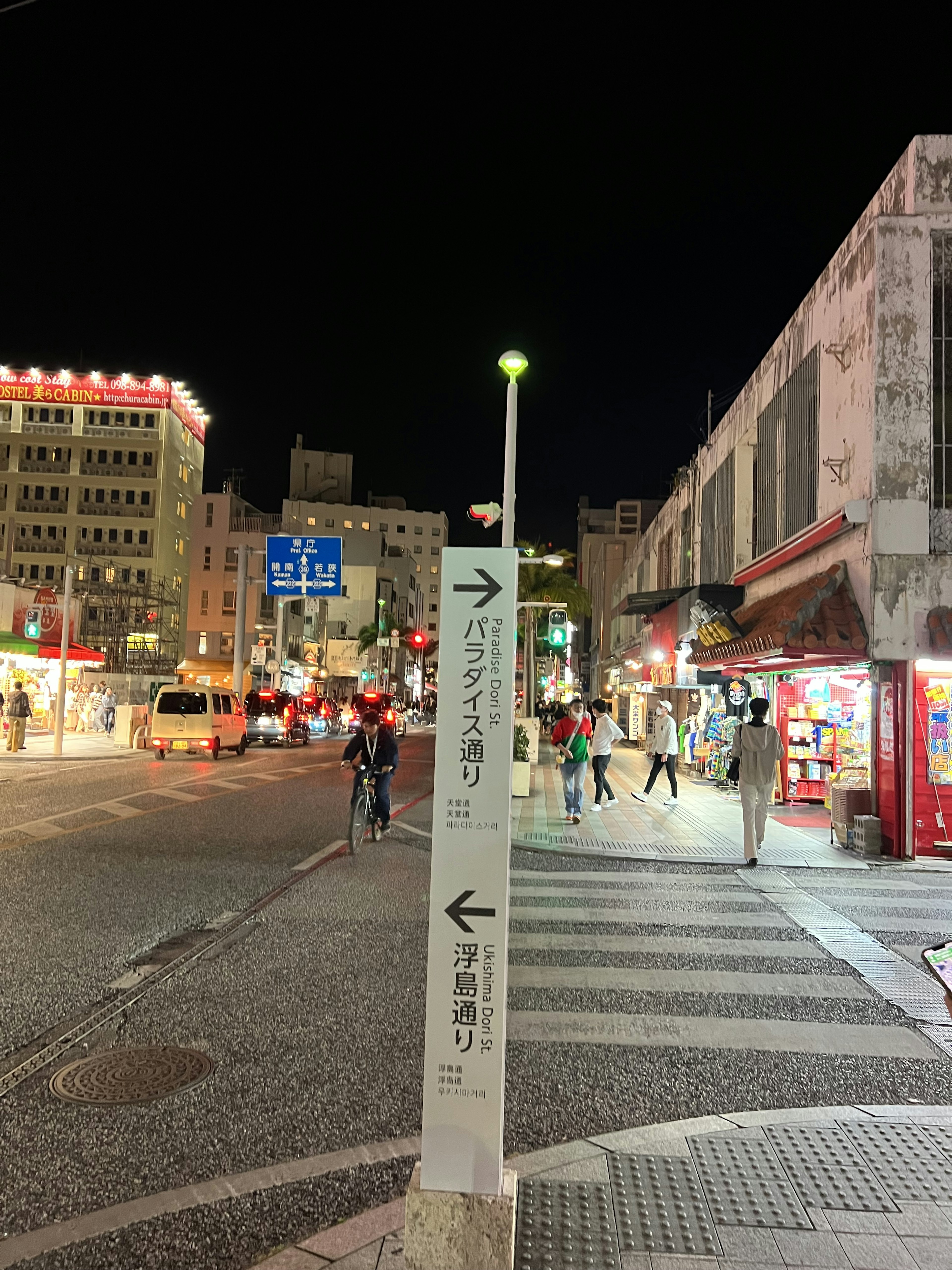 Street sign at night with shops in the background