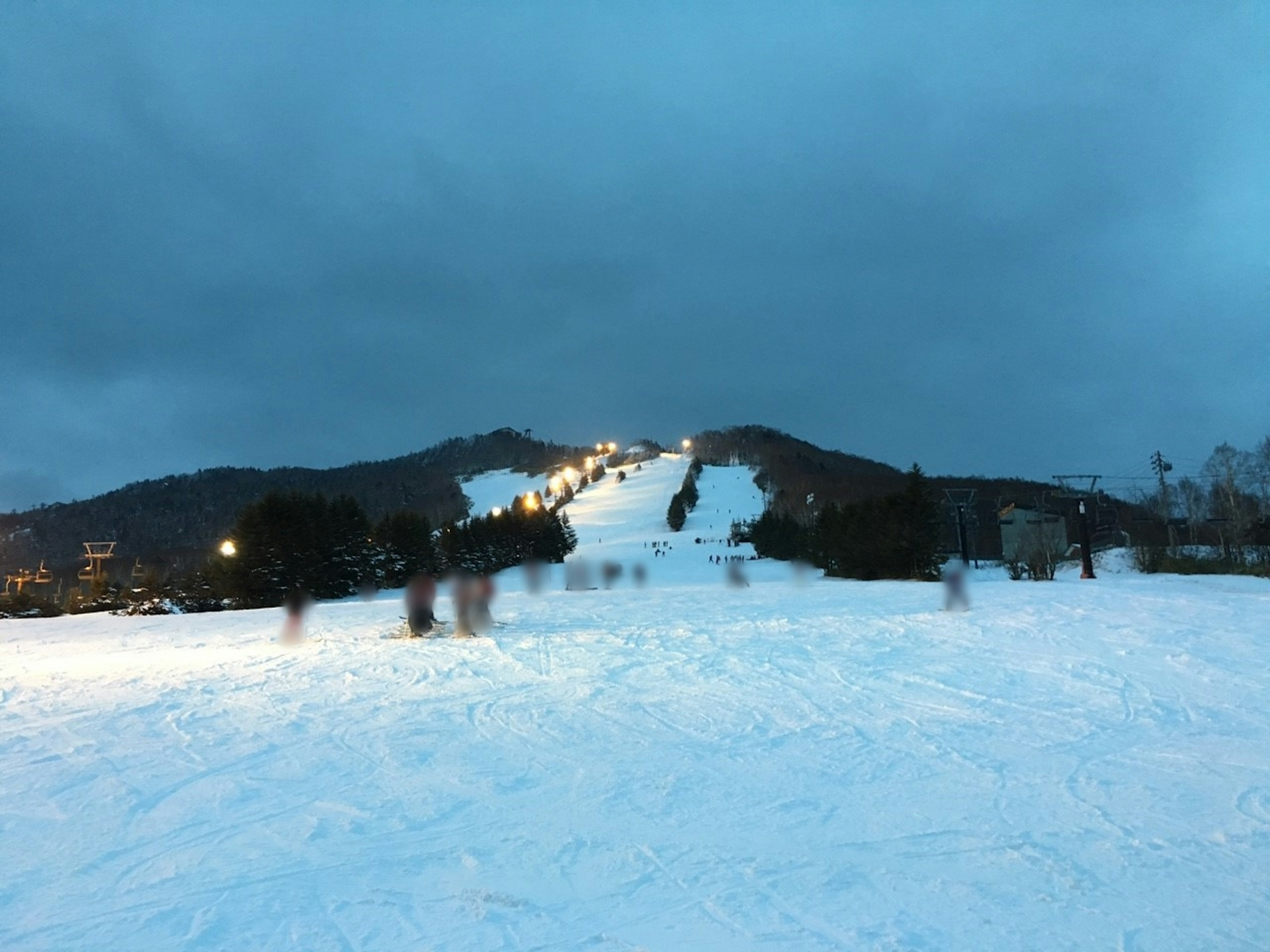 Night view of a snowy ski resort with lights on the slope