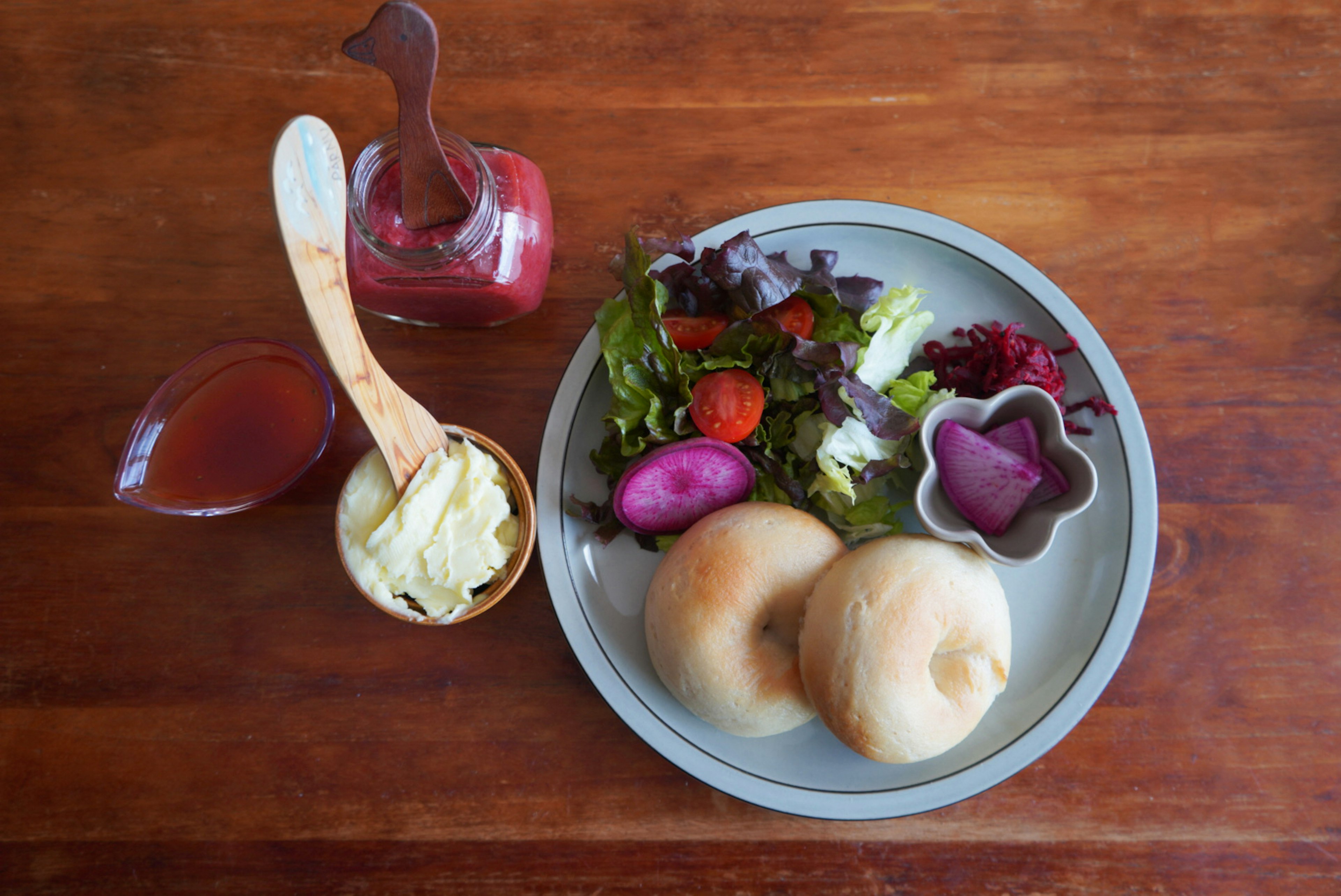 A plate with salad and rolls alongside a sauce bottle