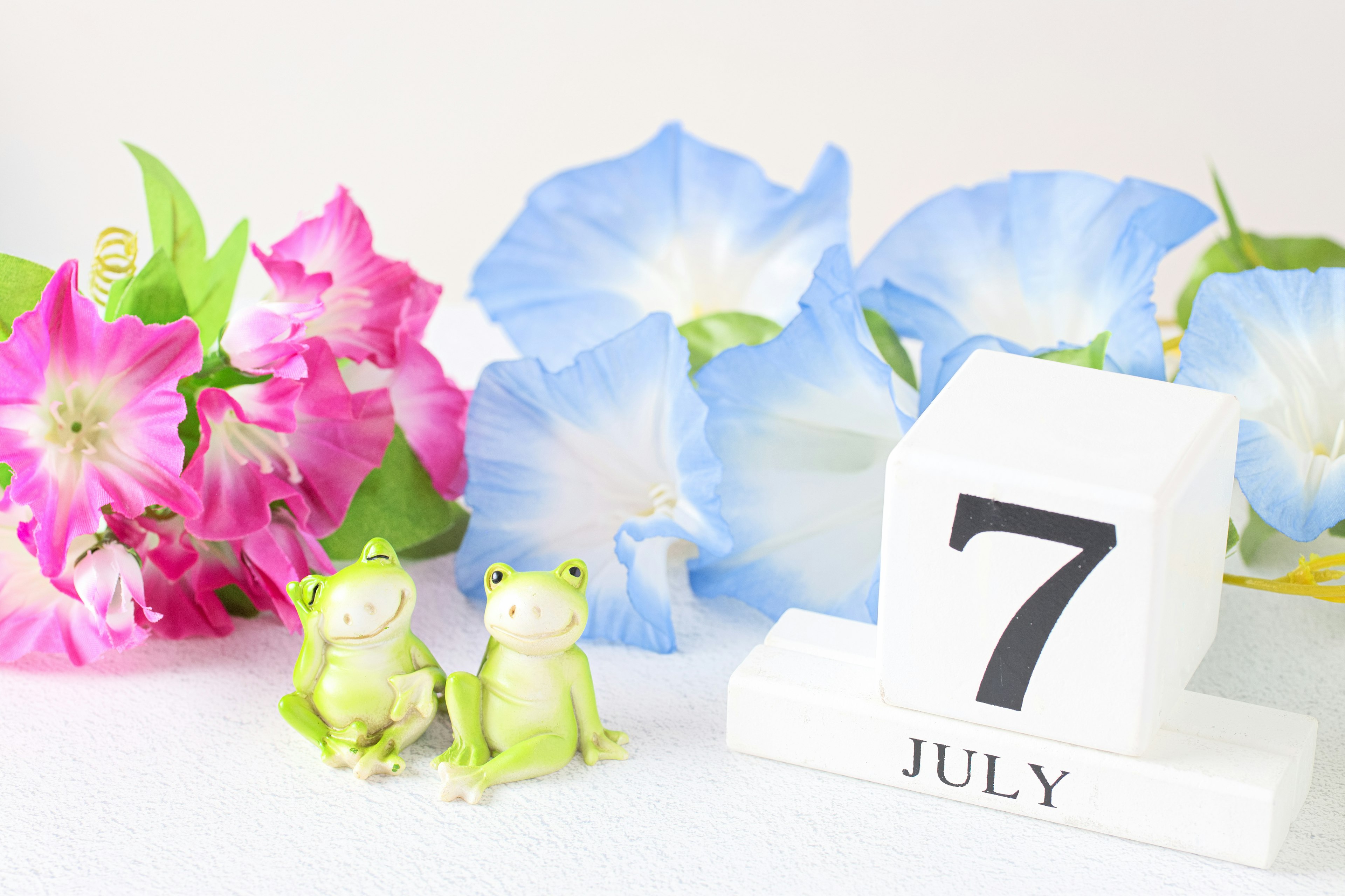 Colorful flowers and frog figurines with a July calendar