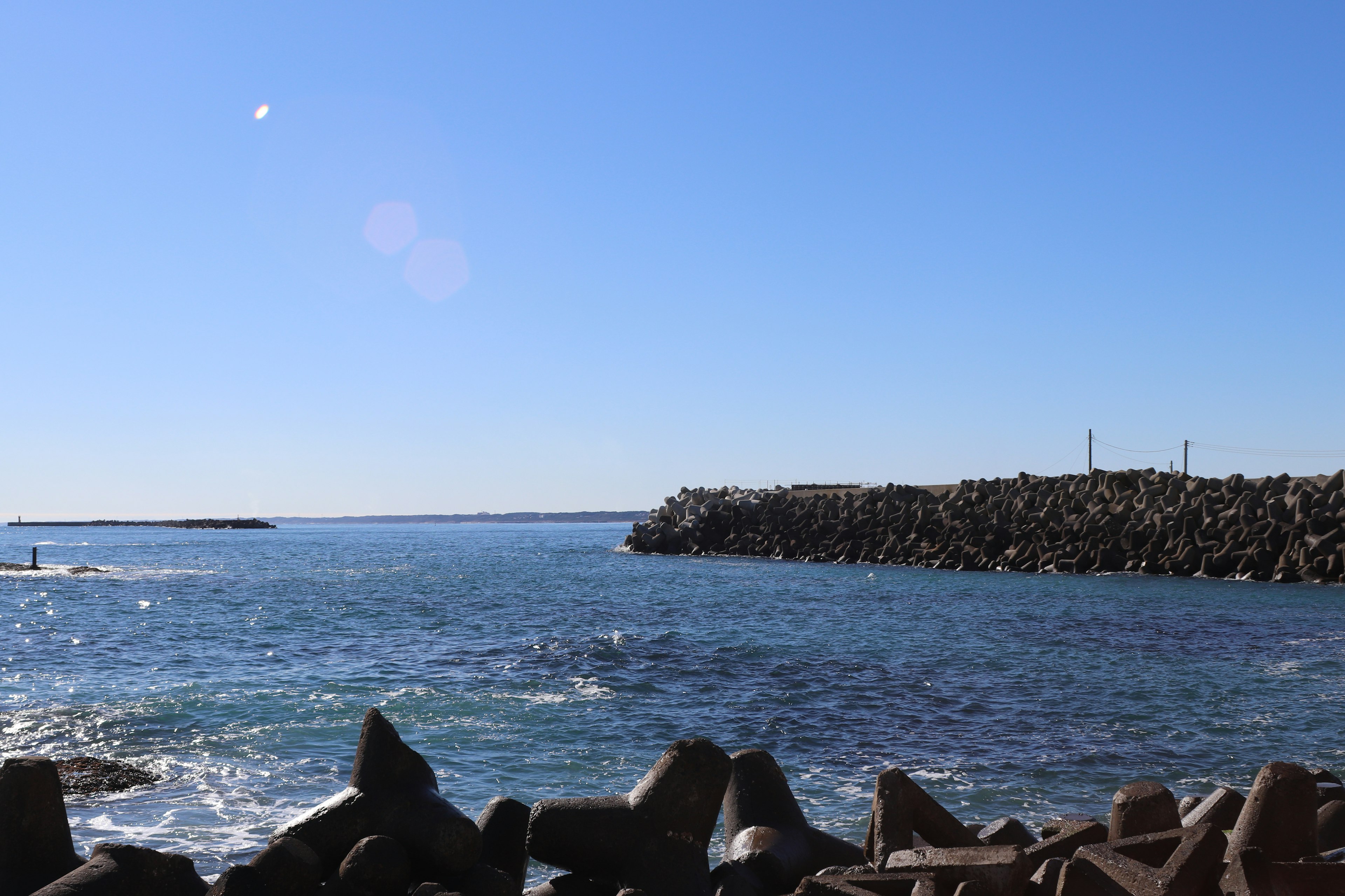 Malersicher Blick auf das blaue Meer und den Wellenbrecher unter einem sonnigen Himmel