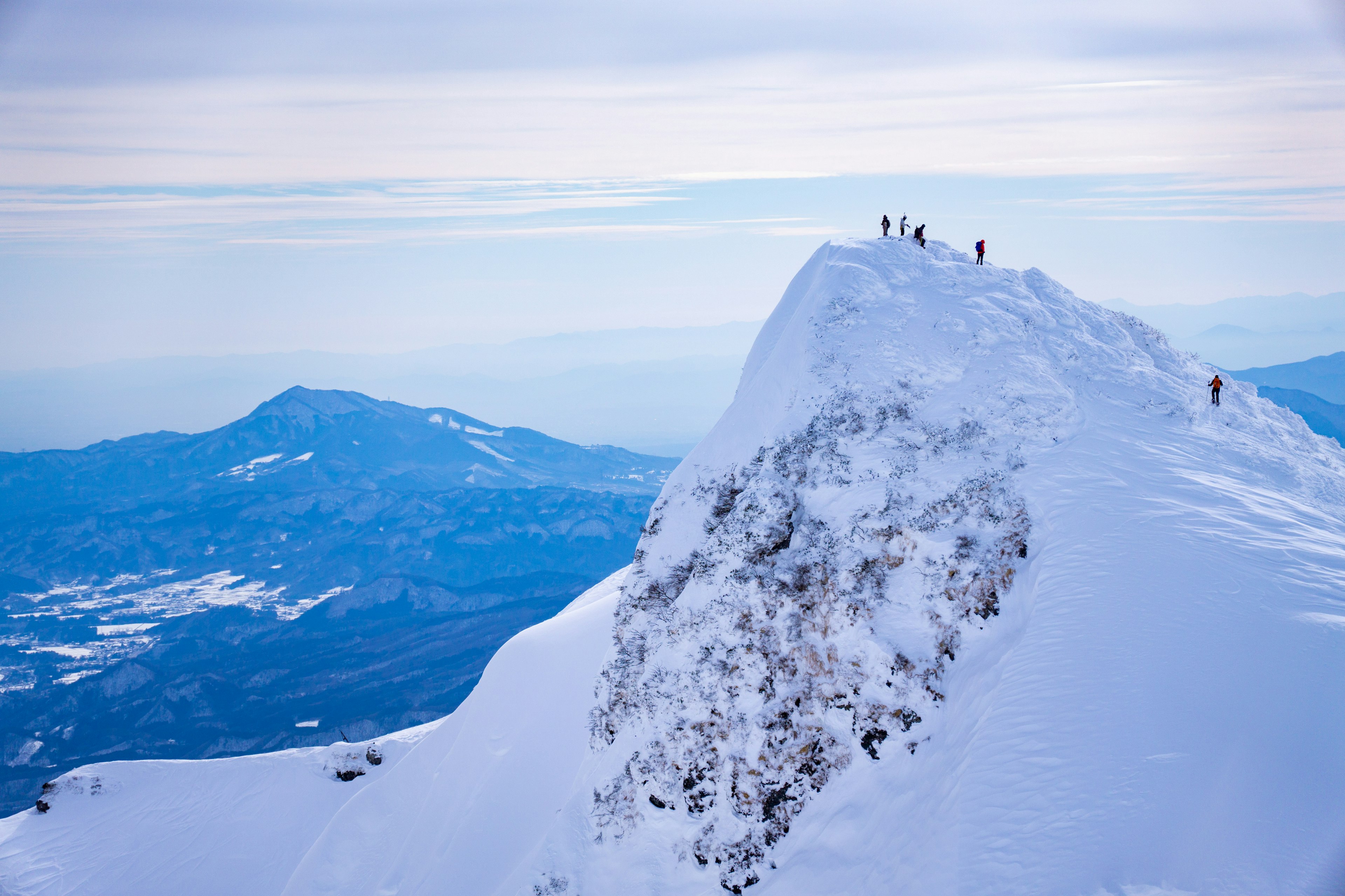 Climbers standing on a snowy mountain peak with a stunning landscape