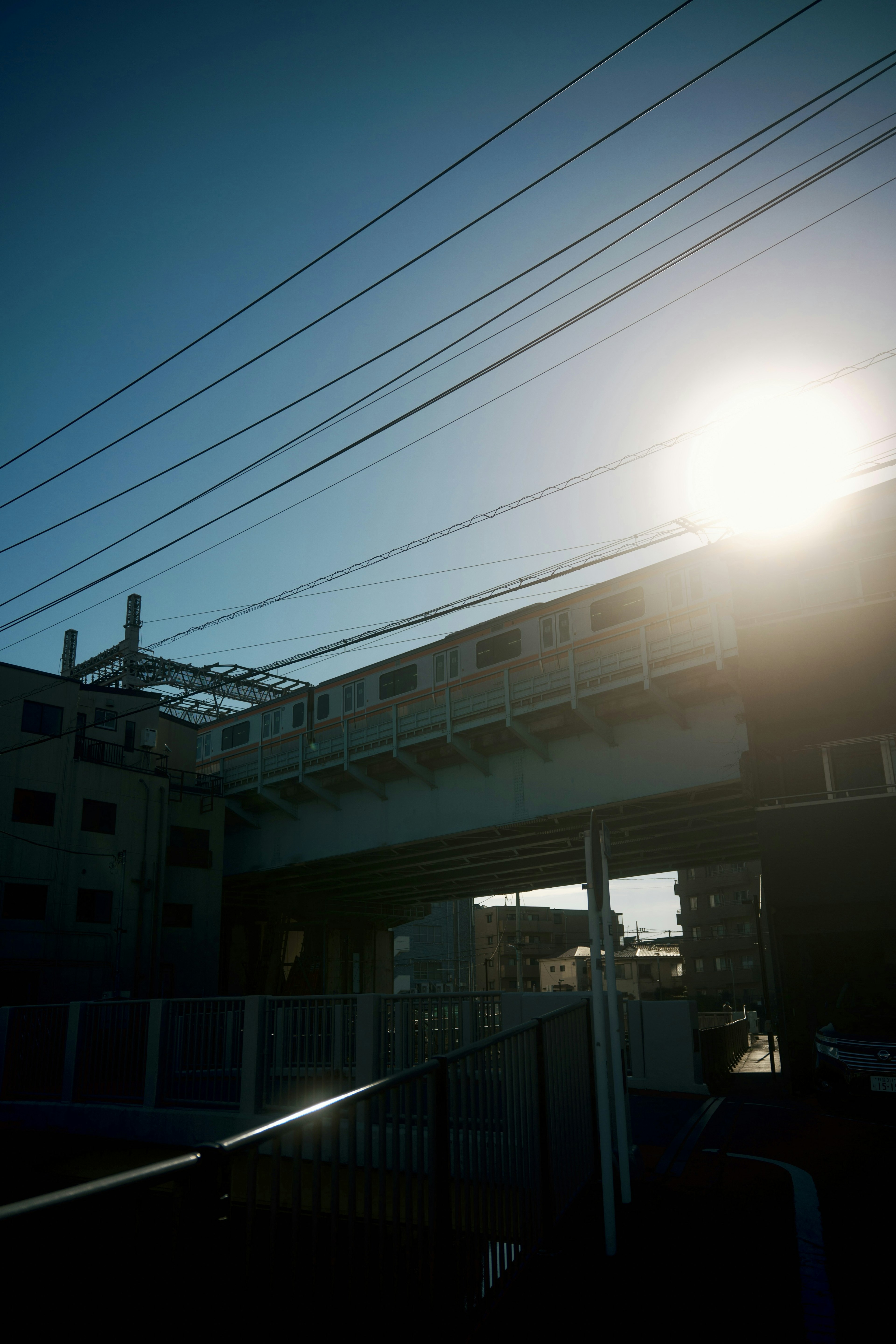 A train running on an elevated track under a blue sky with a shining sun