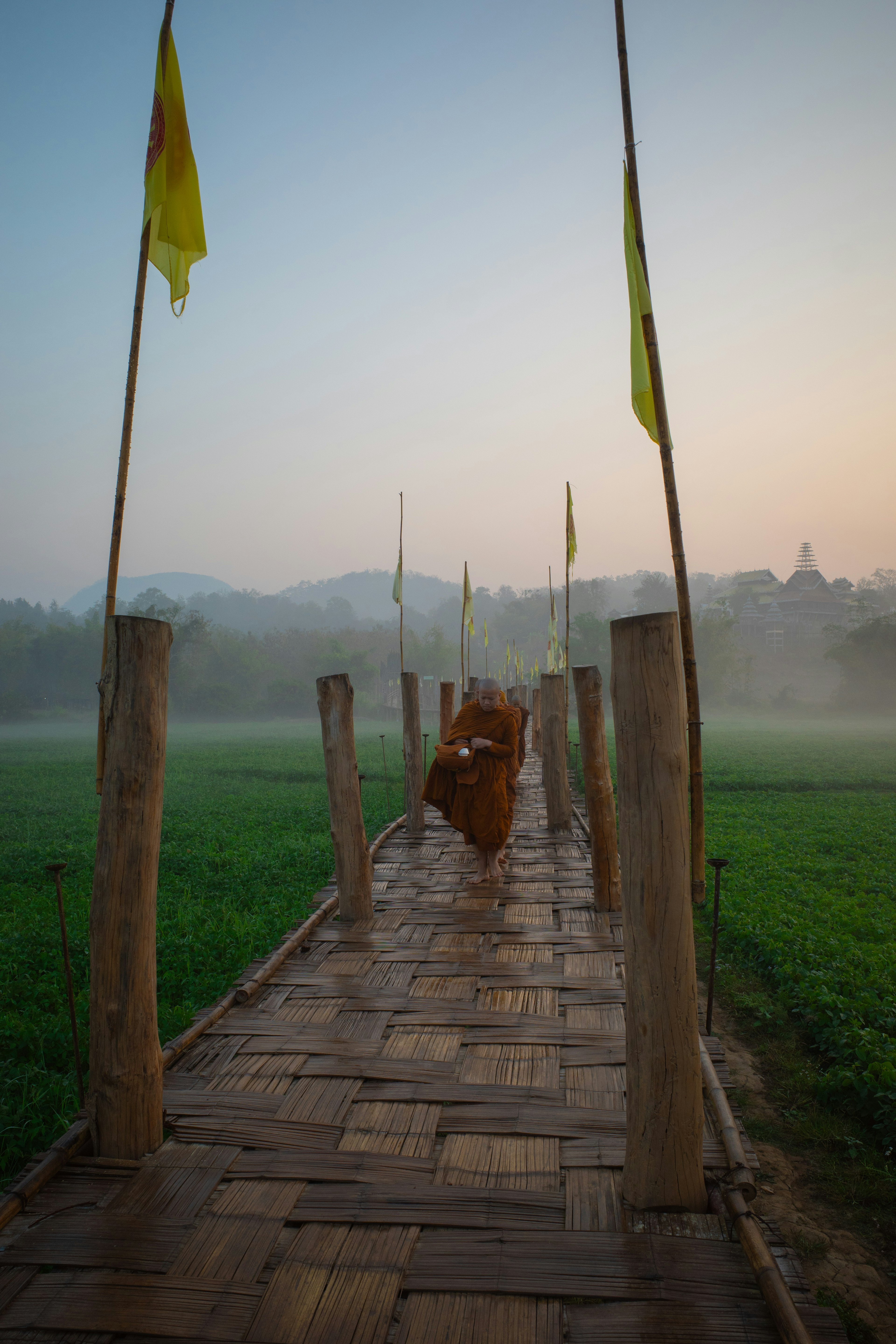 Monk walking on a bamboo bridge in misty morning