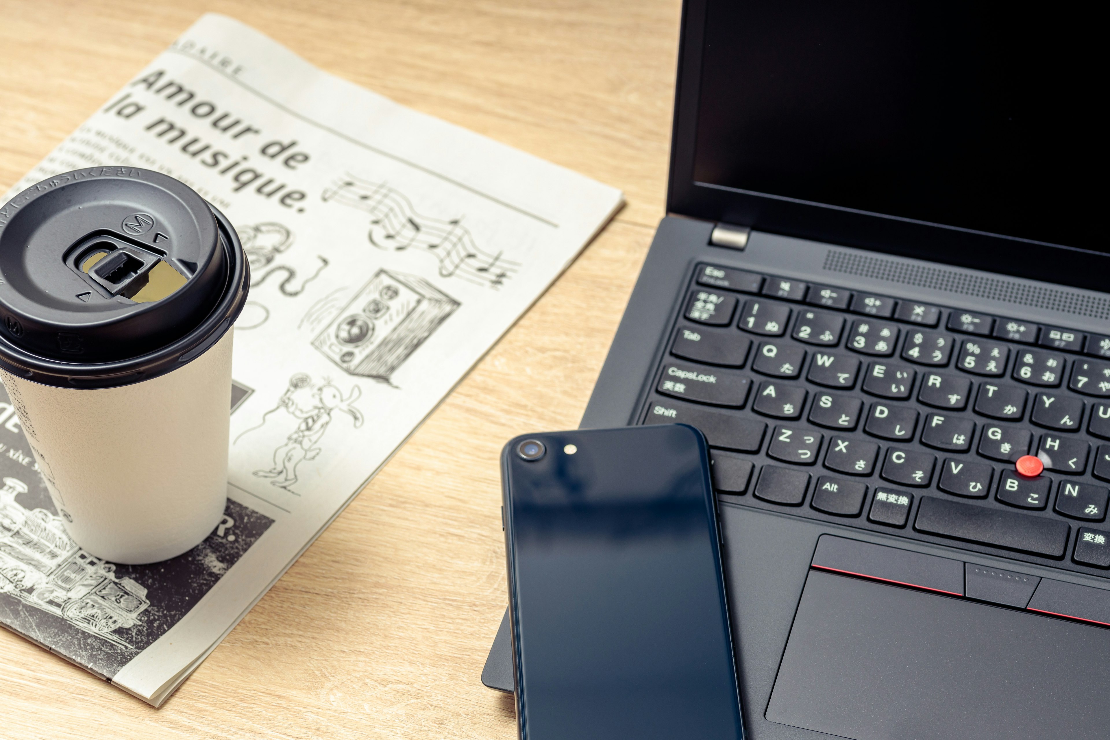 Una escena de escritorio con una taza de café un periódico una computadora portátil y un teléfono inteligente dispuestos ordenadamente