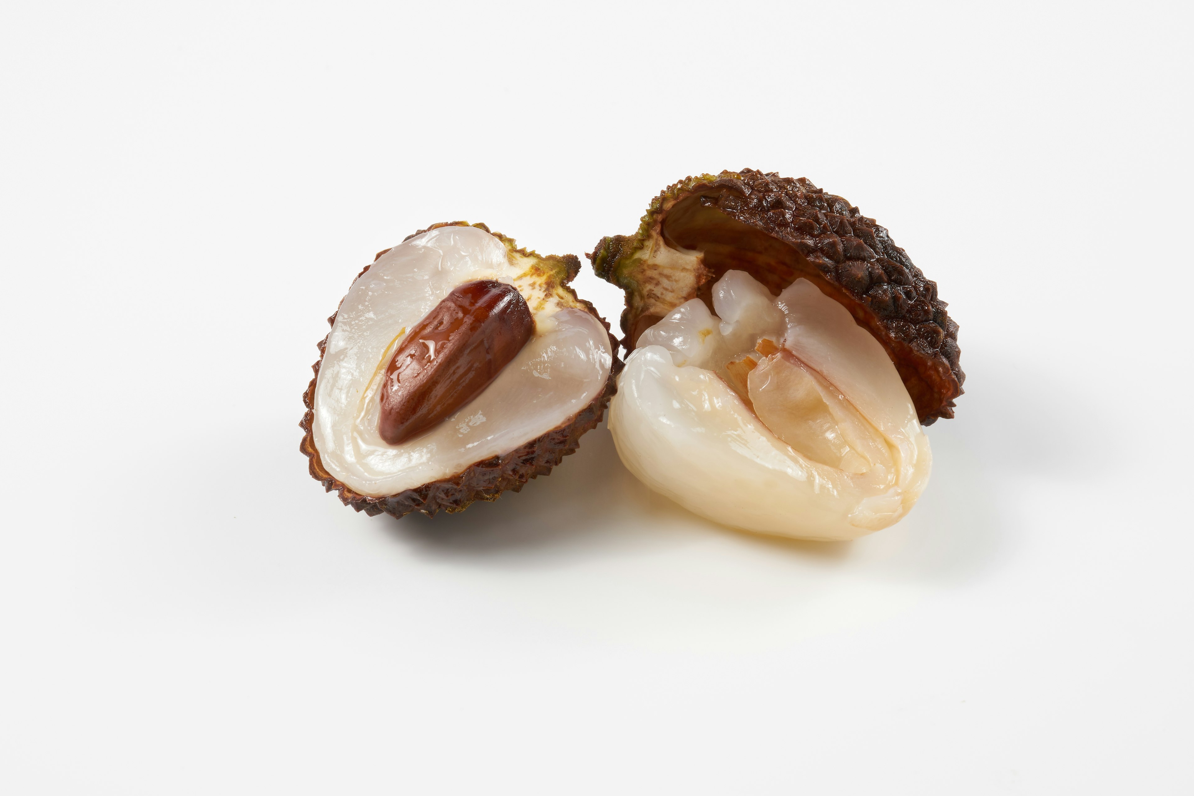 Cut lychee fruit with seed on a white background