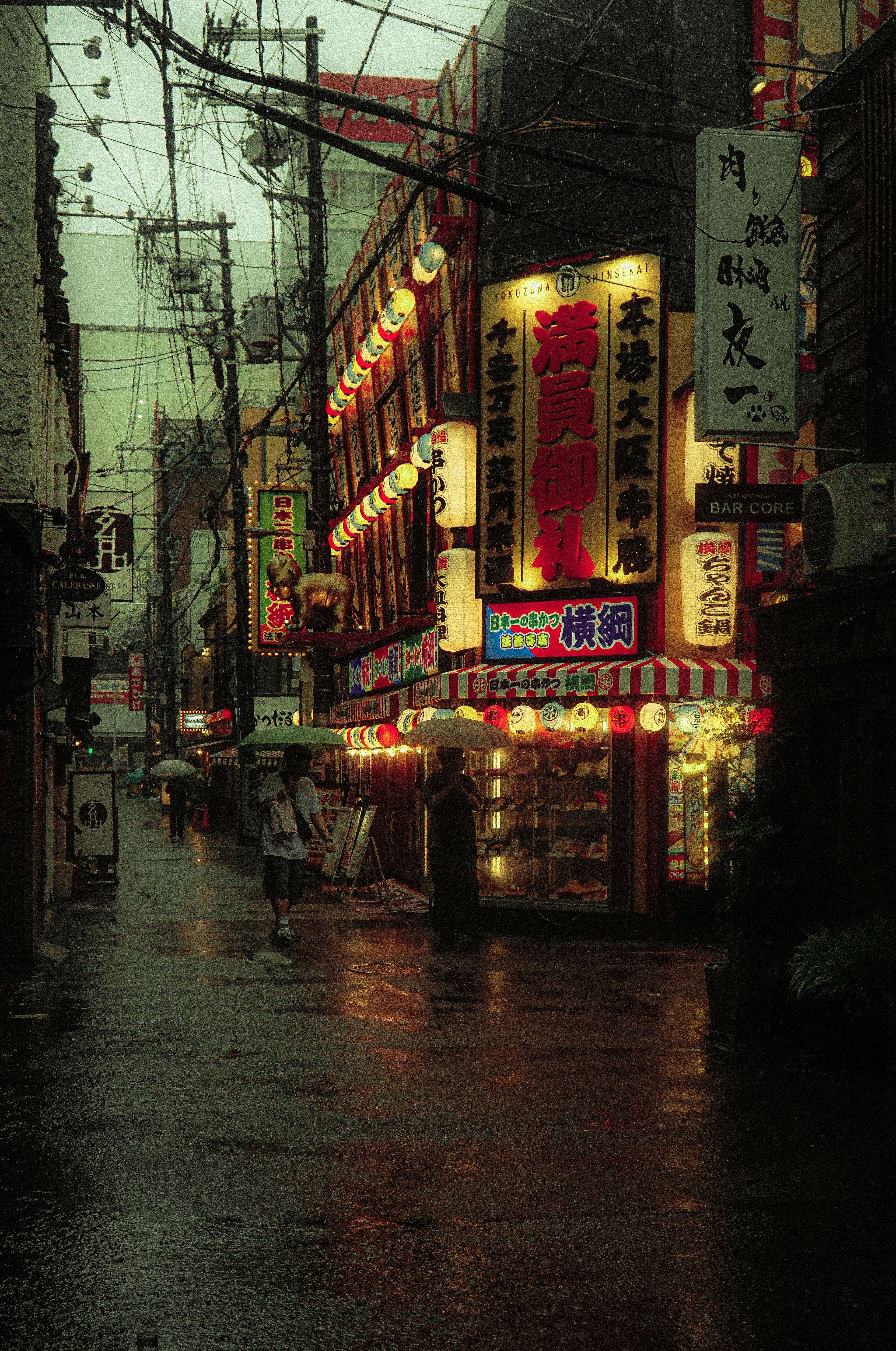 Escena animada de una calle comercial bajo la lluvia Carteles brillantes y farolillos coloridos bordean la calle