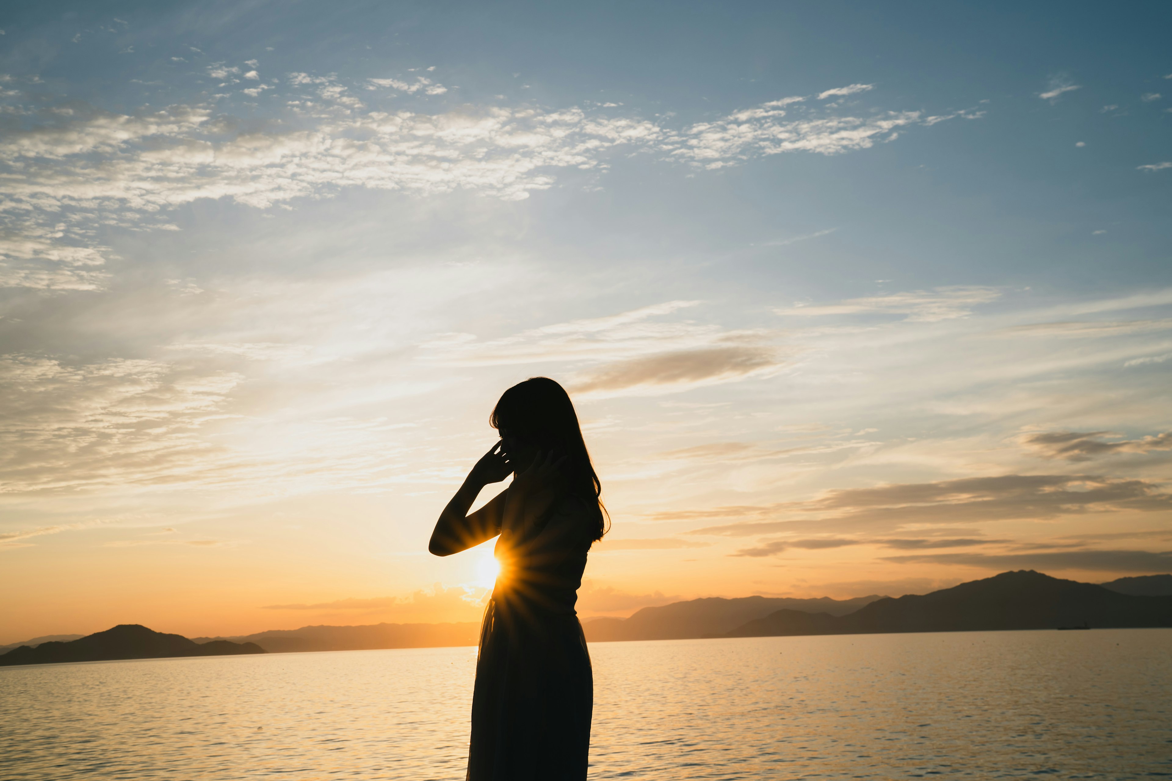 Silhouette einer Frau gegen einen Sonnenuntergang über dem Ozean