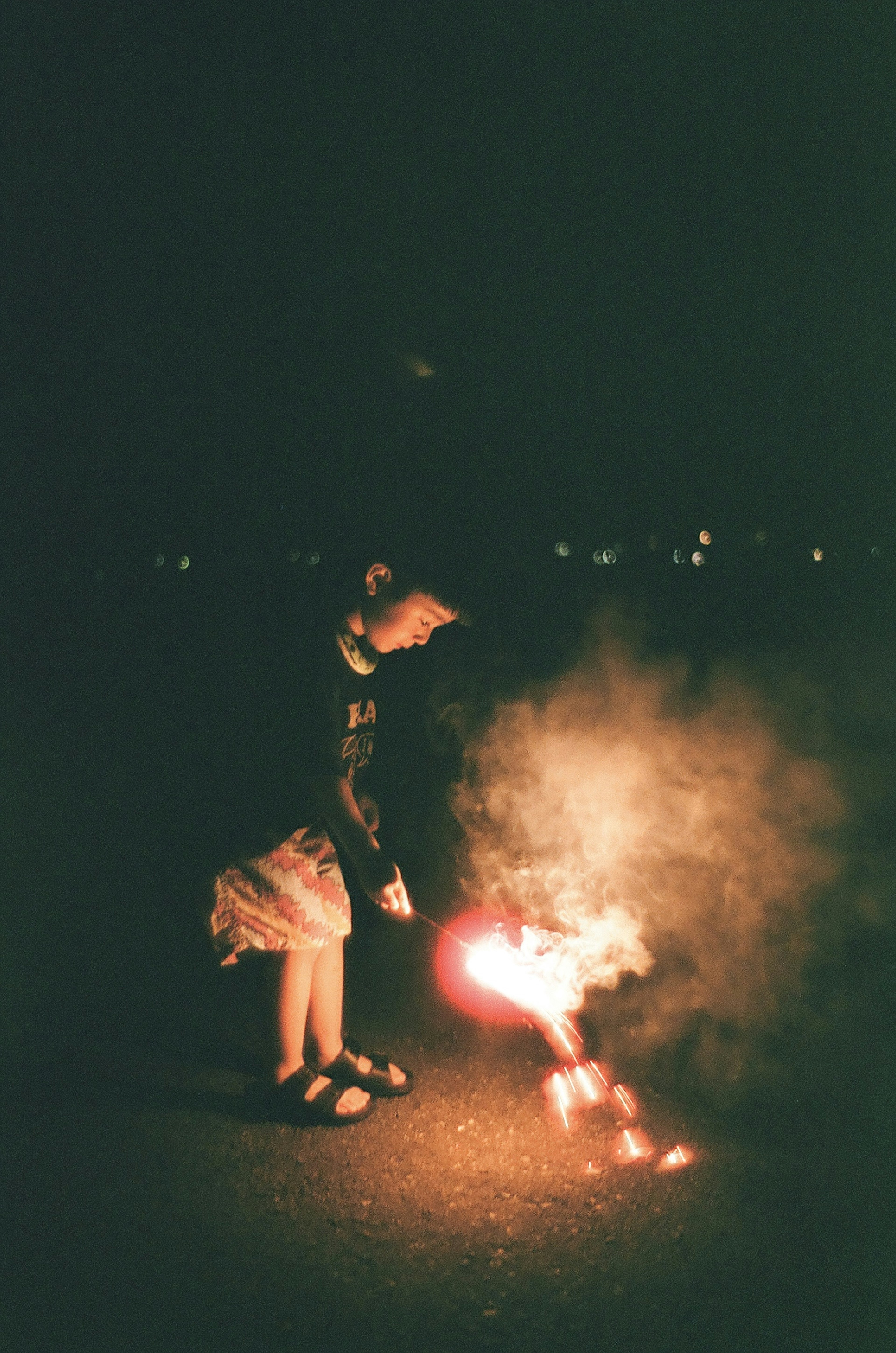 Niño sosteniendo un fuego artificial en un entorno oscuro