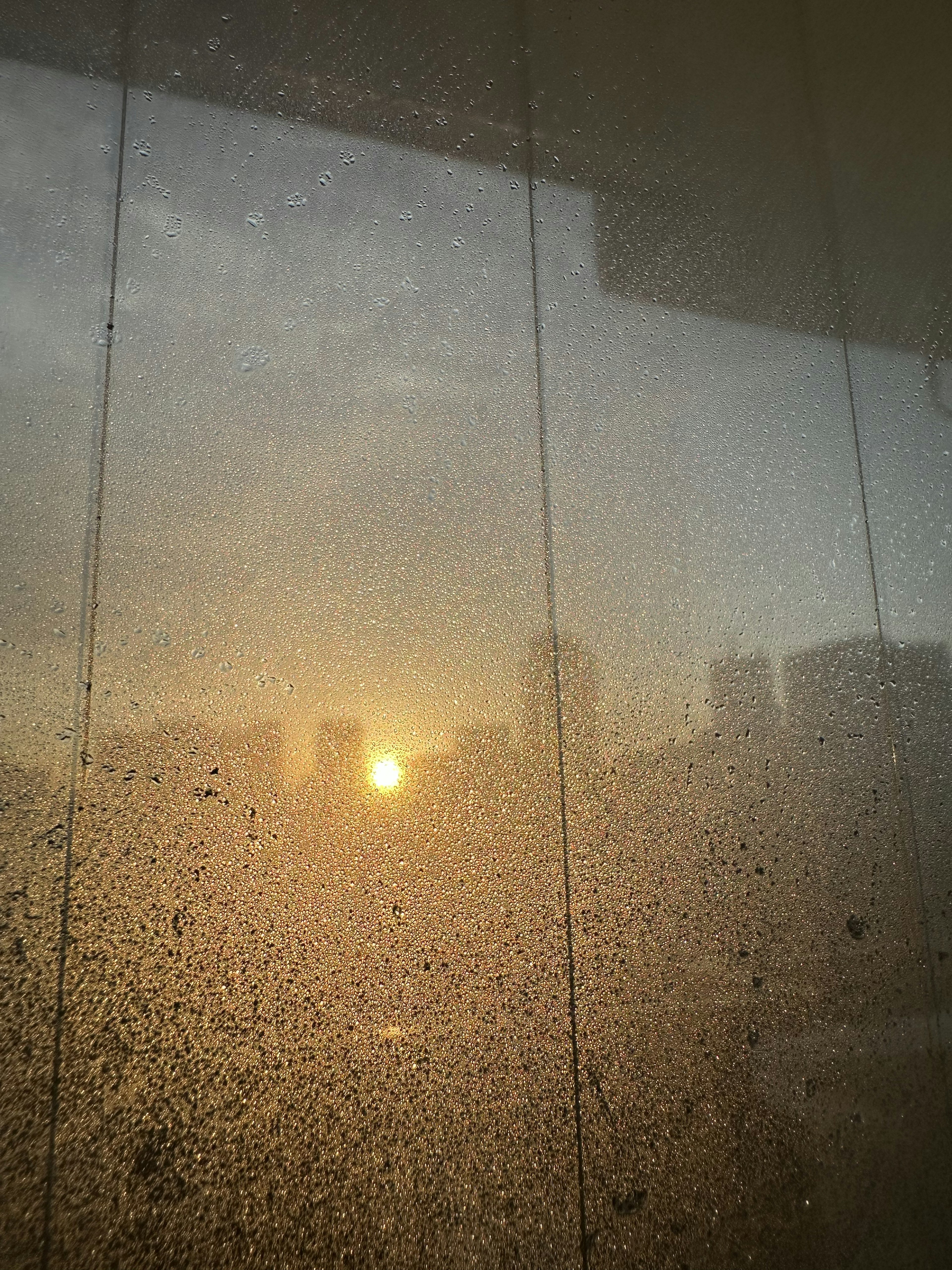 Atardecer visto a través de una ventana empañada con una silueta de ciudad