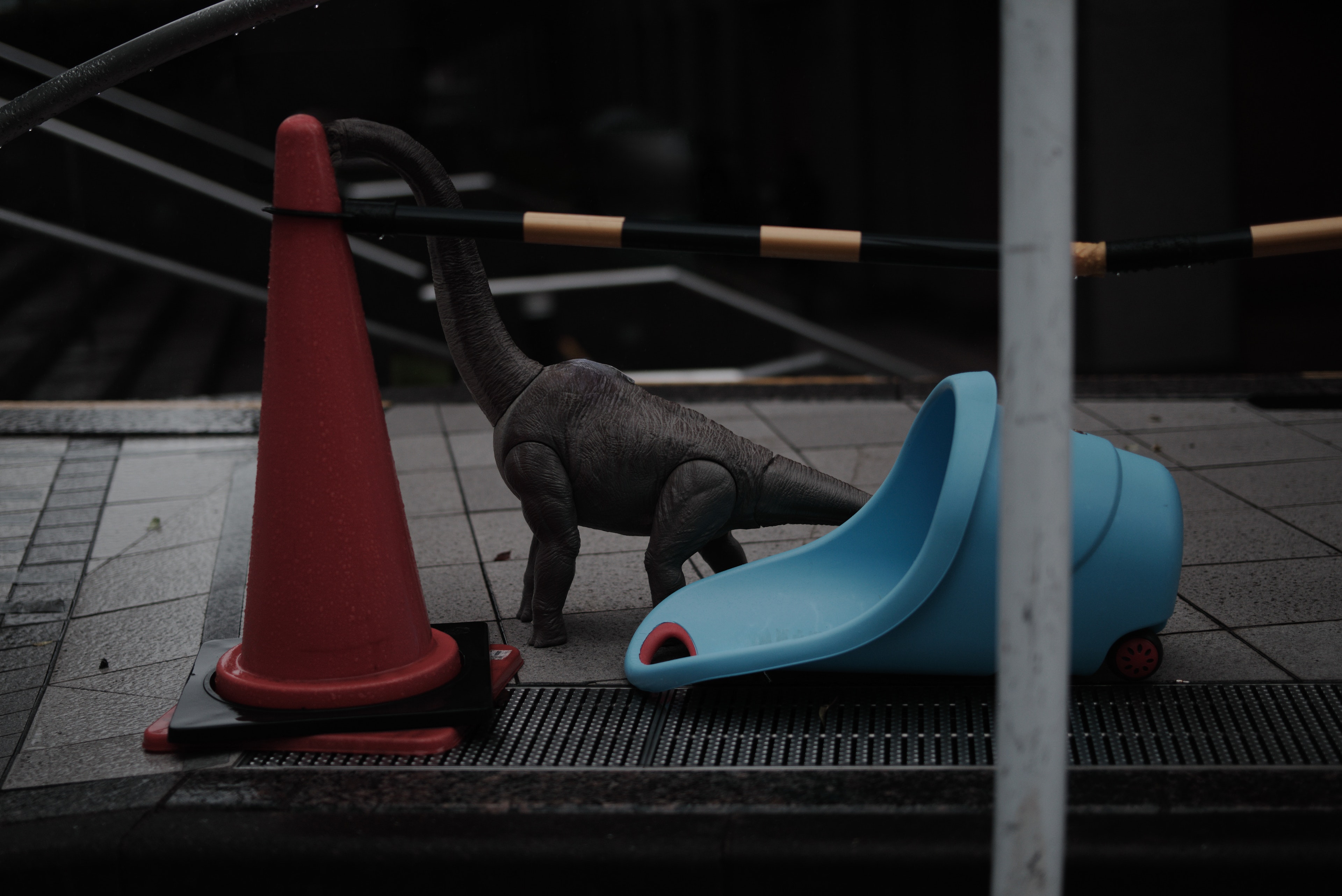 A dinosaur toy near a red cone and a blue slide