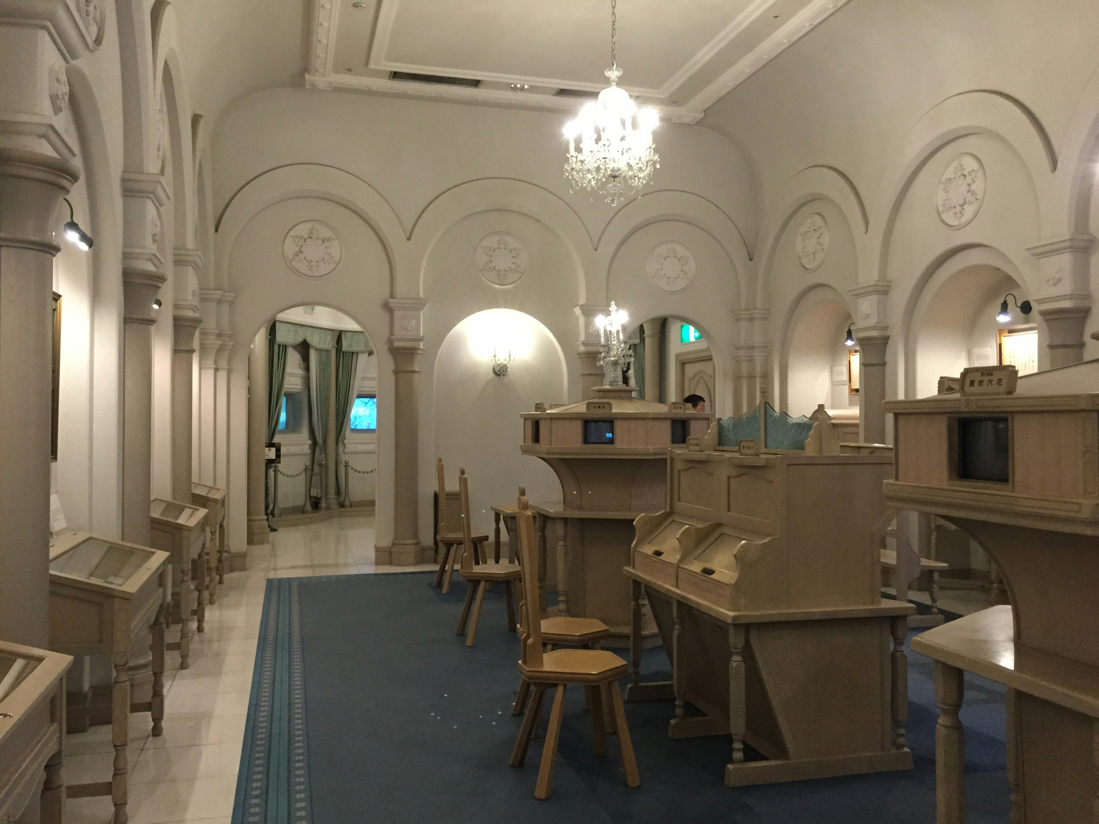 Brightly lit interior featuring wooden furniture and a chandelier in a quiet library-like room