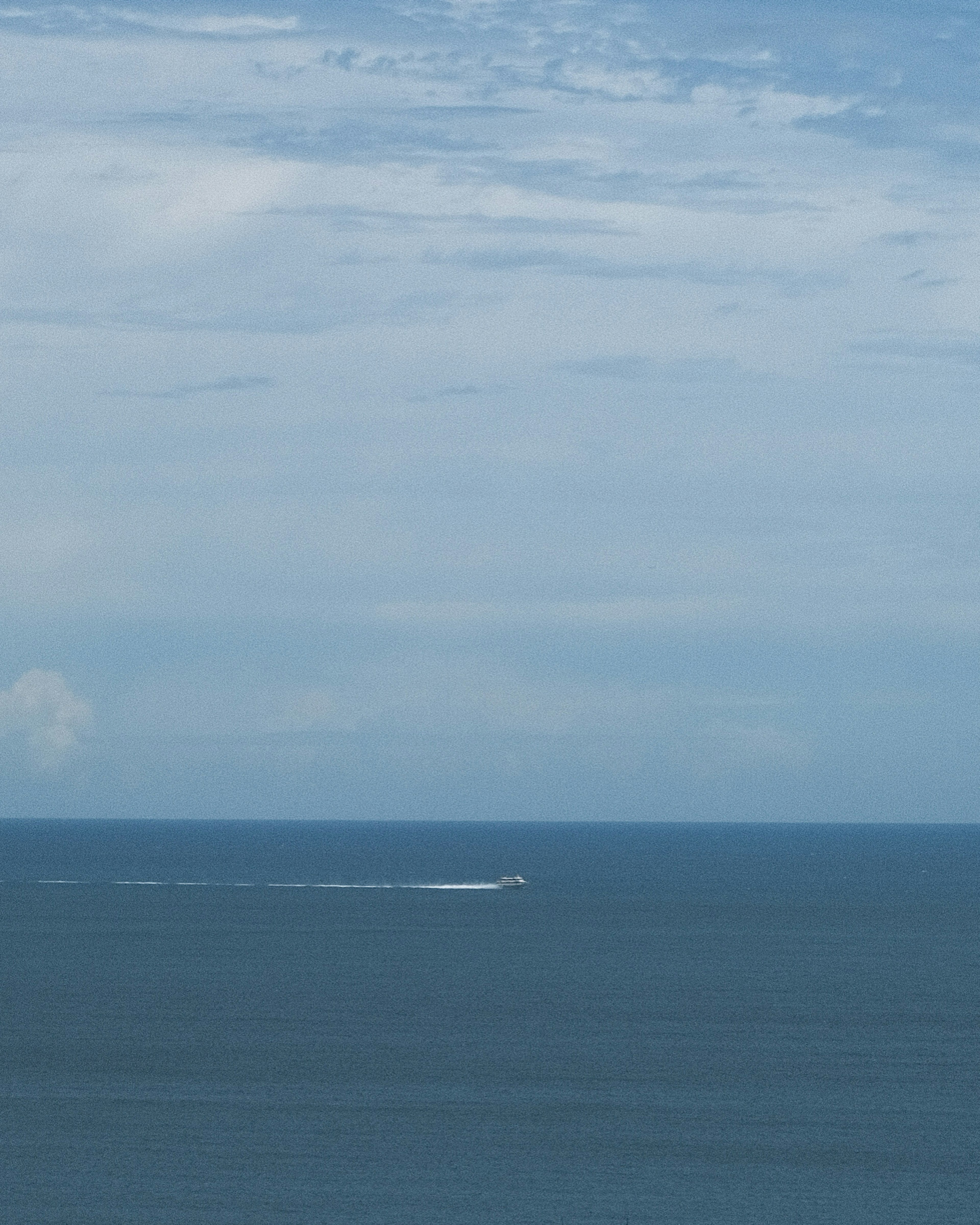 Pequeño barco en un océano azul con un cielo nublado