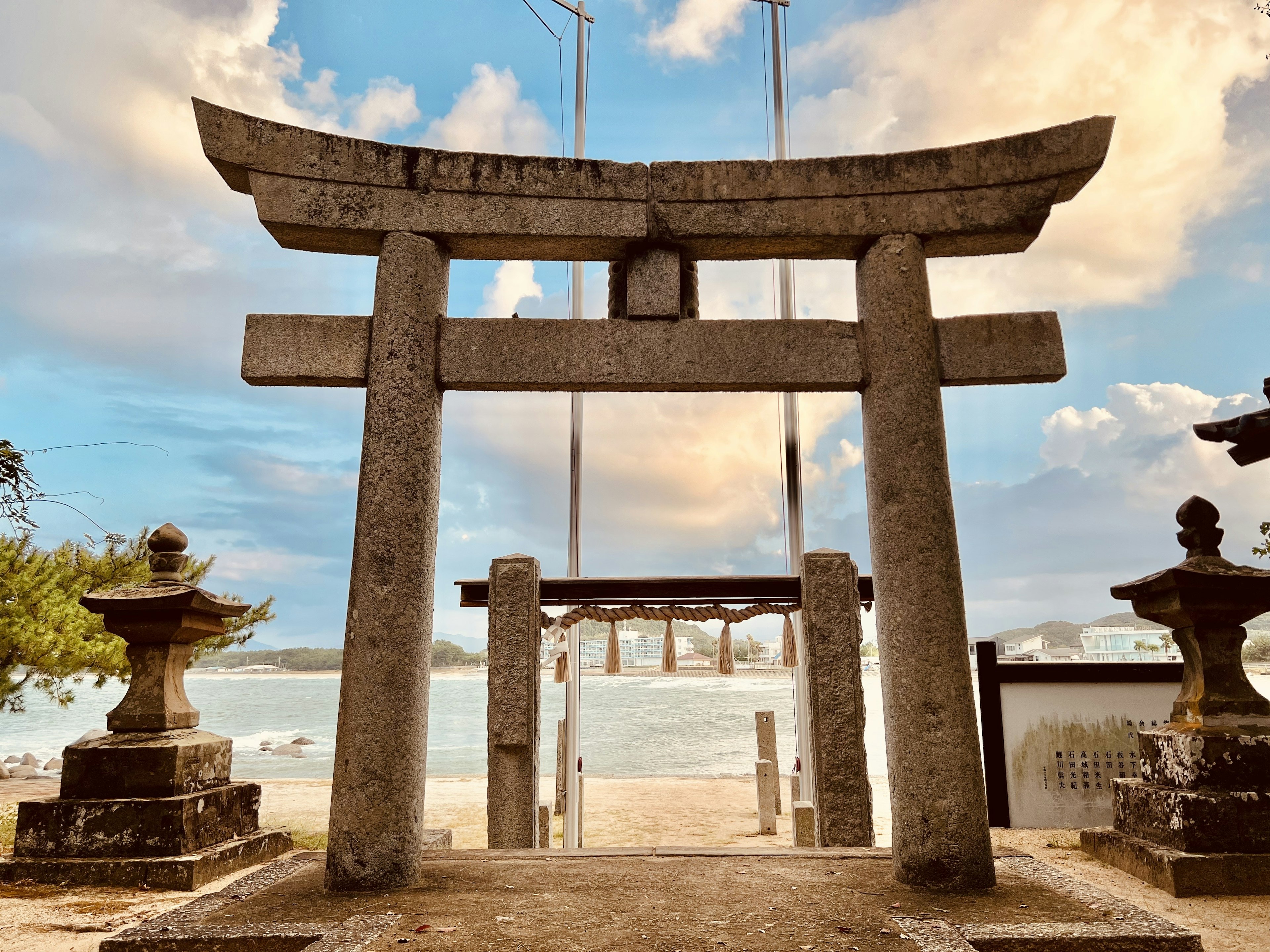 Stone torii gate and lanterns by the sea