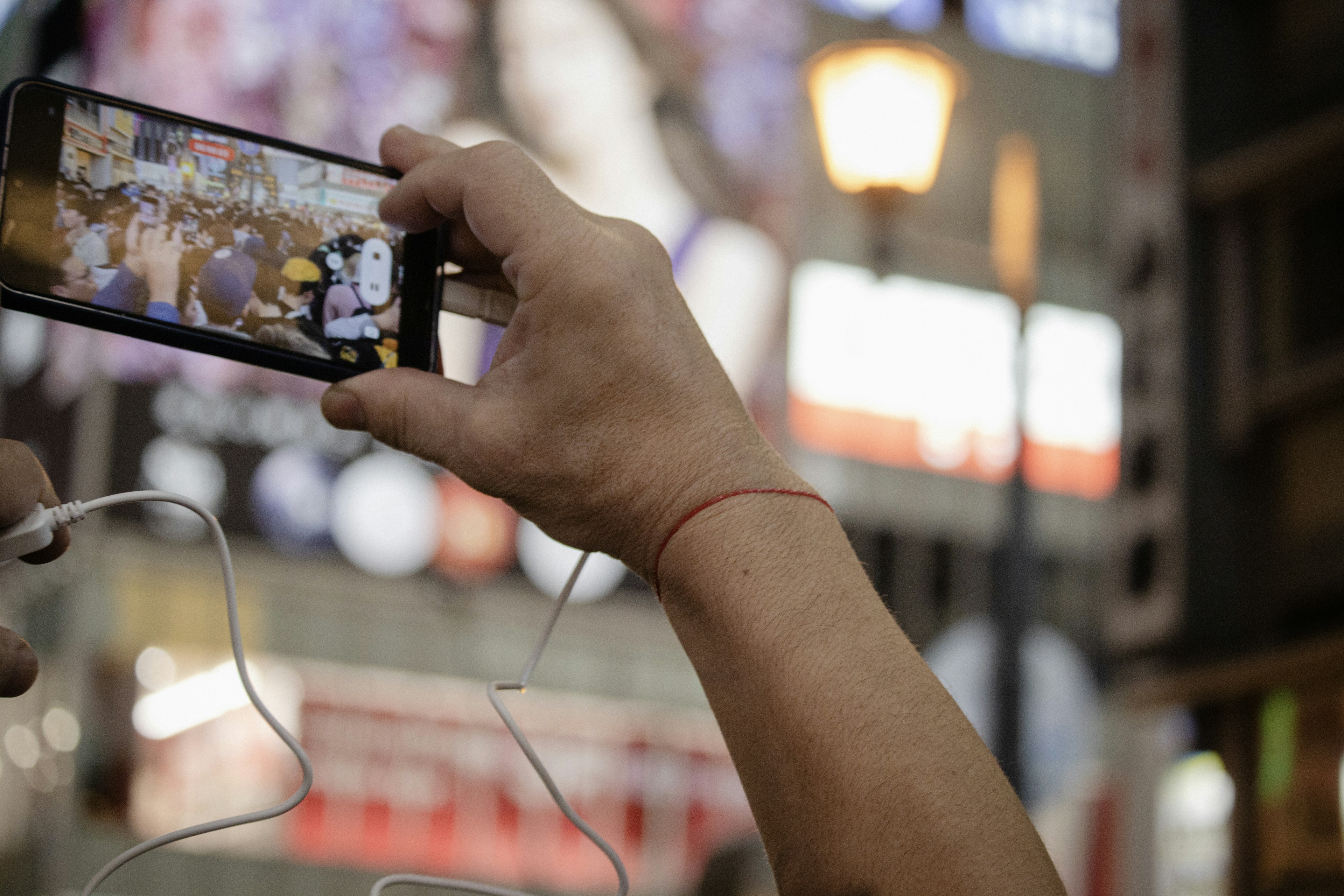 Sebuah tangan memegang smartphone menangkap pemandangan jalan yang hidup