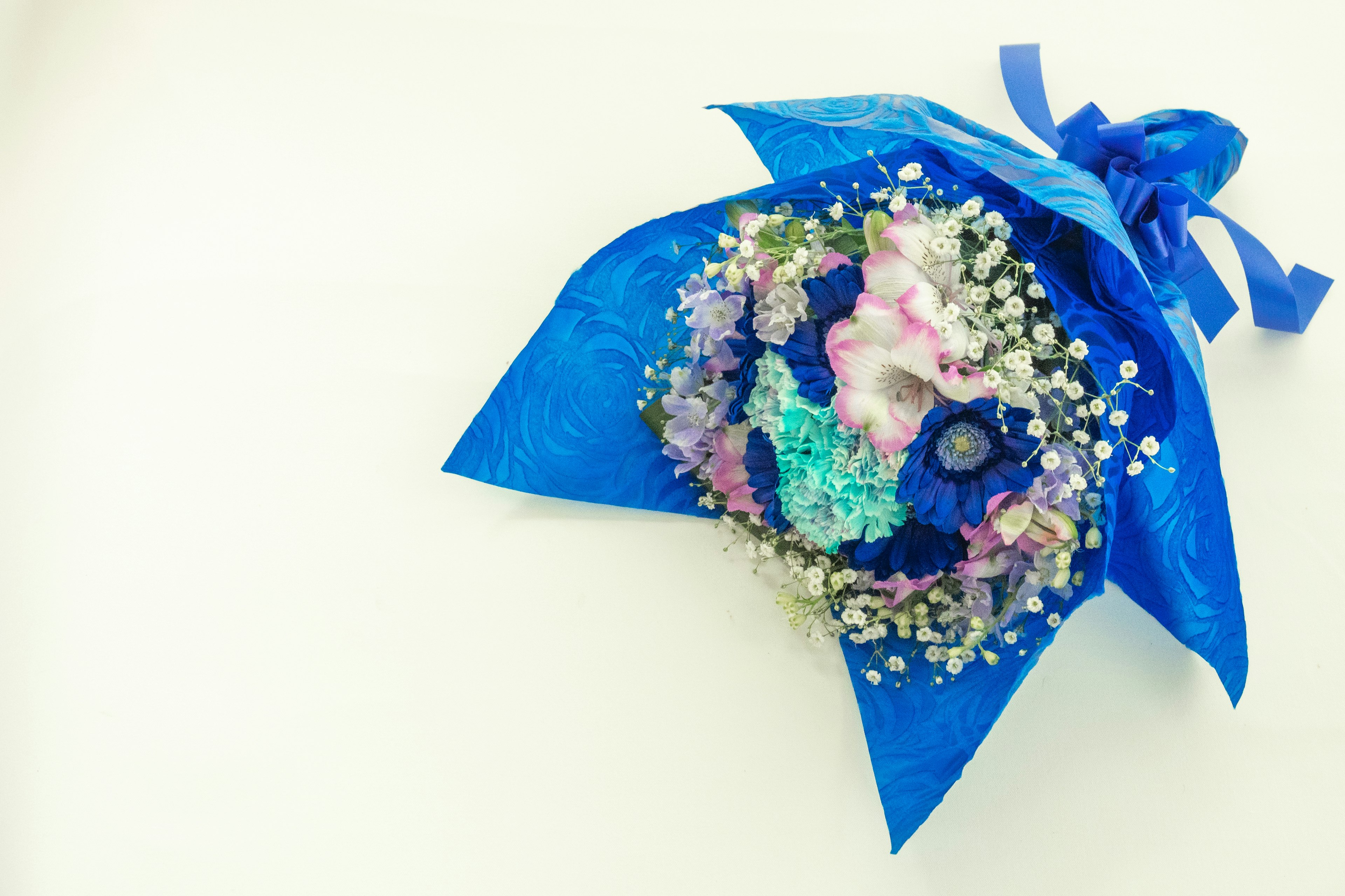 Bouquet avvolto in carta blu con fiori colorati e foglie delicate