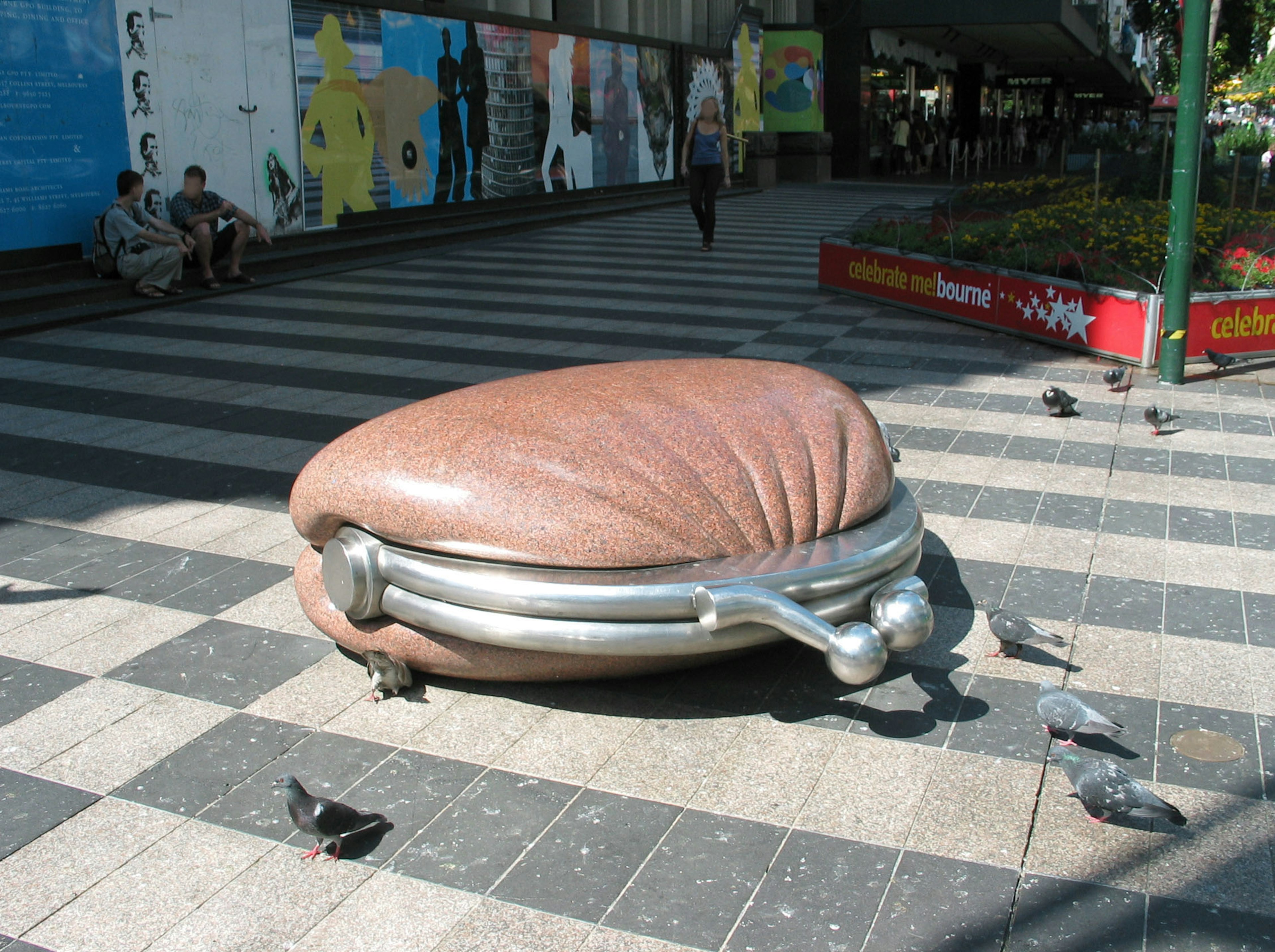 도시 거리의 거대한 조개껍데기 조각과 그 주변의 비둘기들