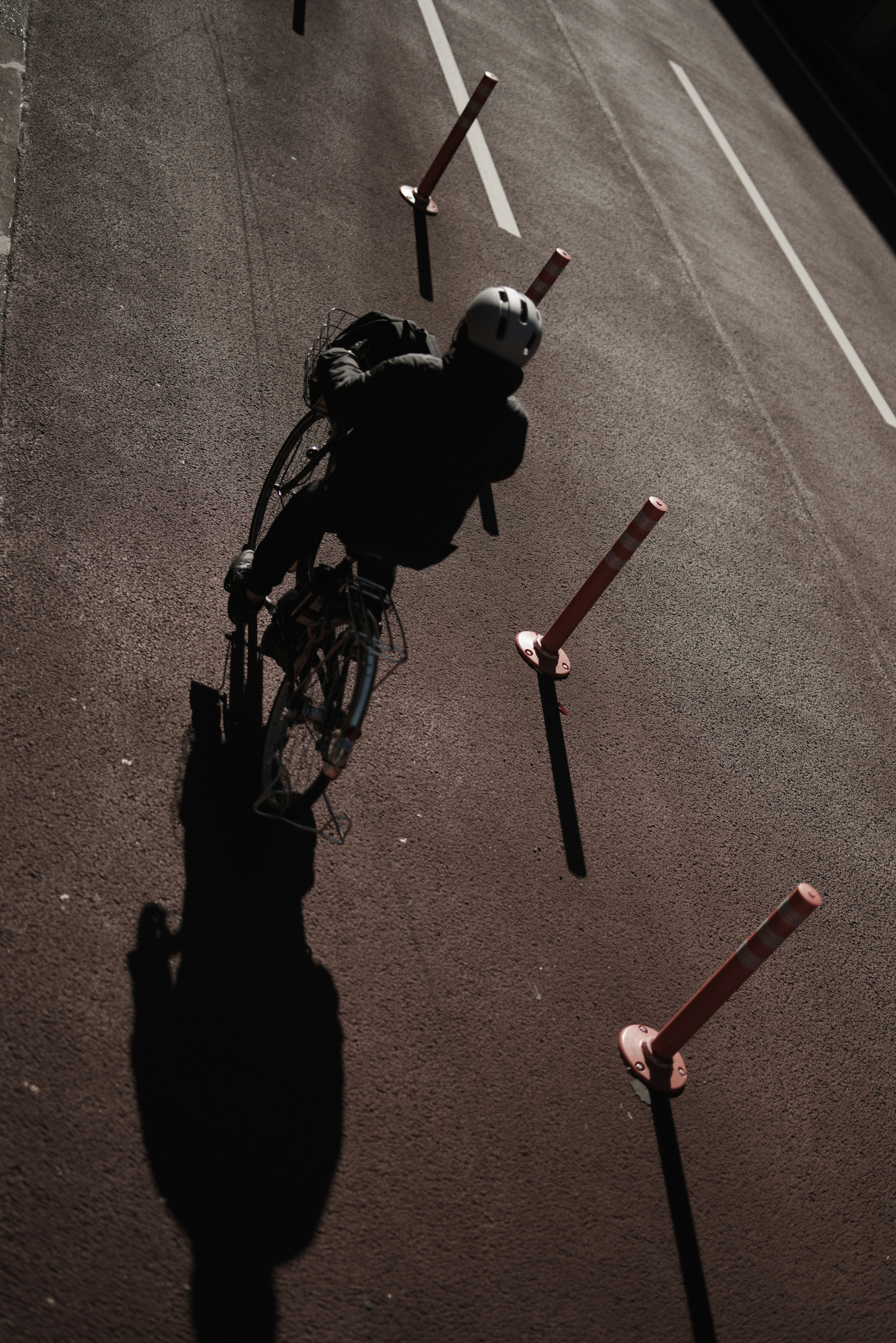 Ein Radfahrer, der einen Schatten auf die Straße mit Verkehrsmarkierungen wirft