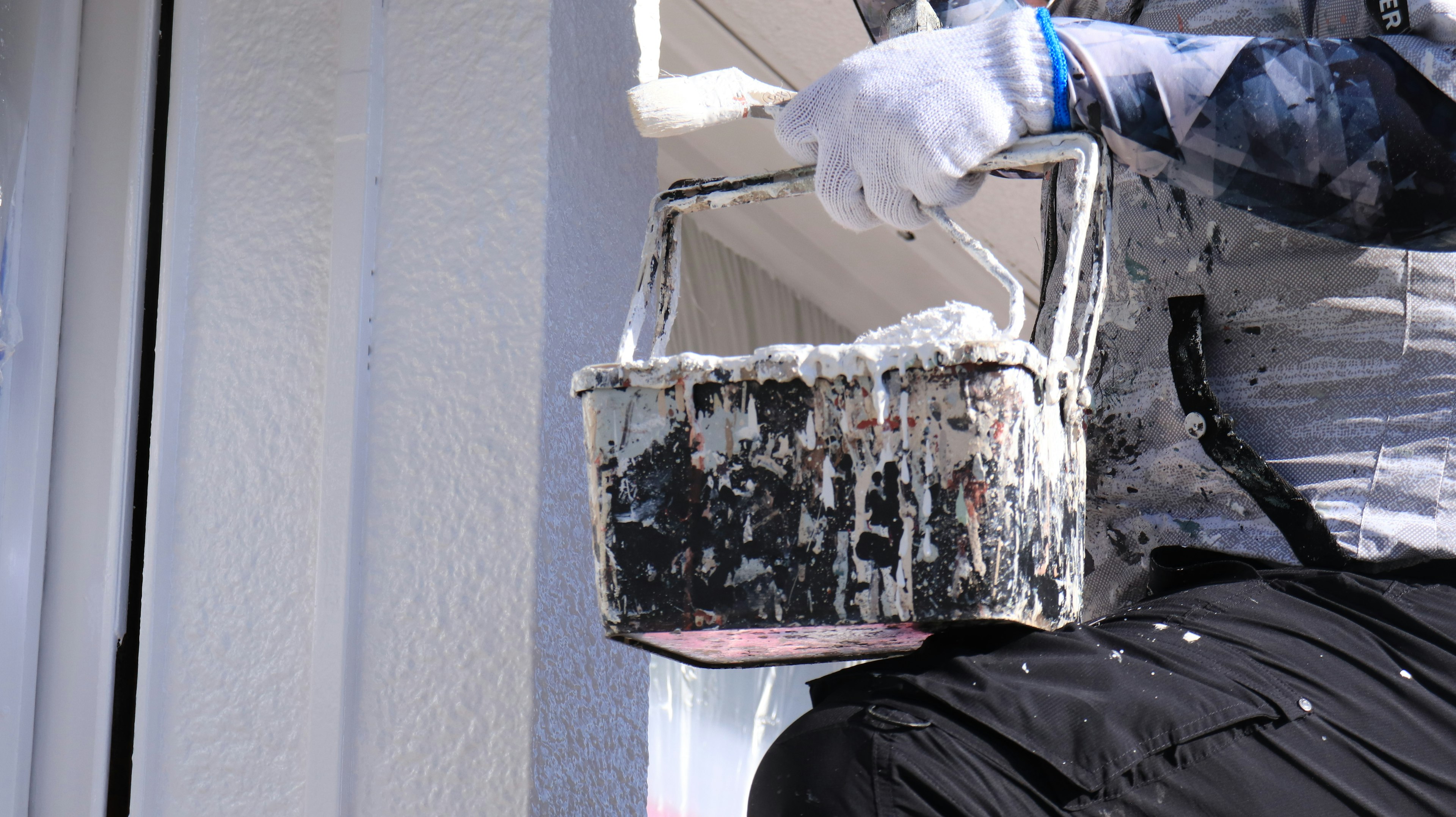 A person holding a paint bucket while painting