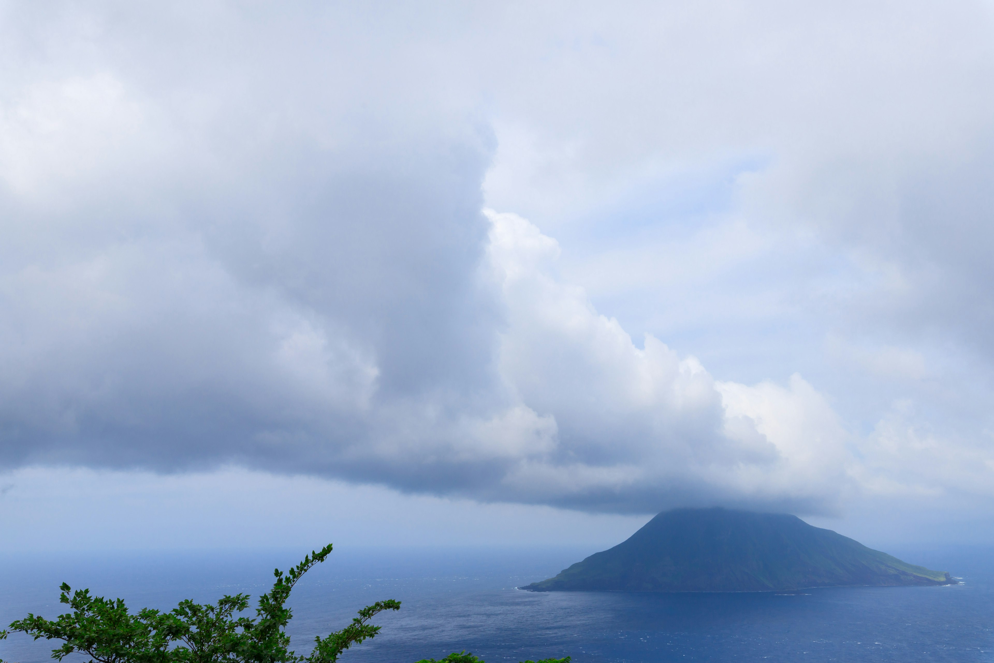 Pulau yang tertutup awan dengan pemandangan lautan biru