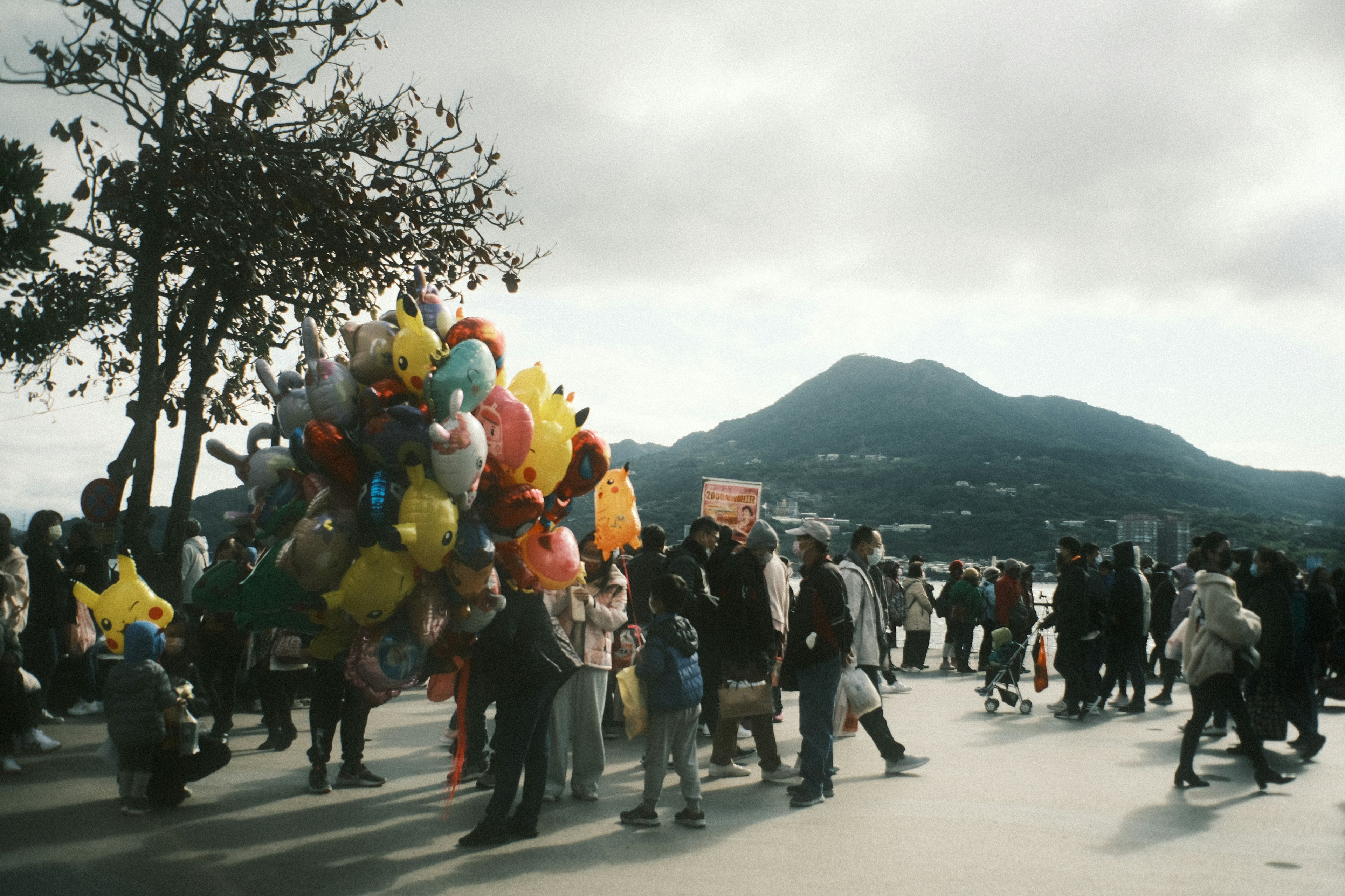 Multitud de personas con globos coloridos cerca de una montaña