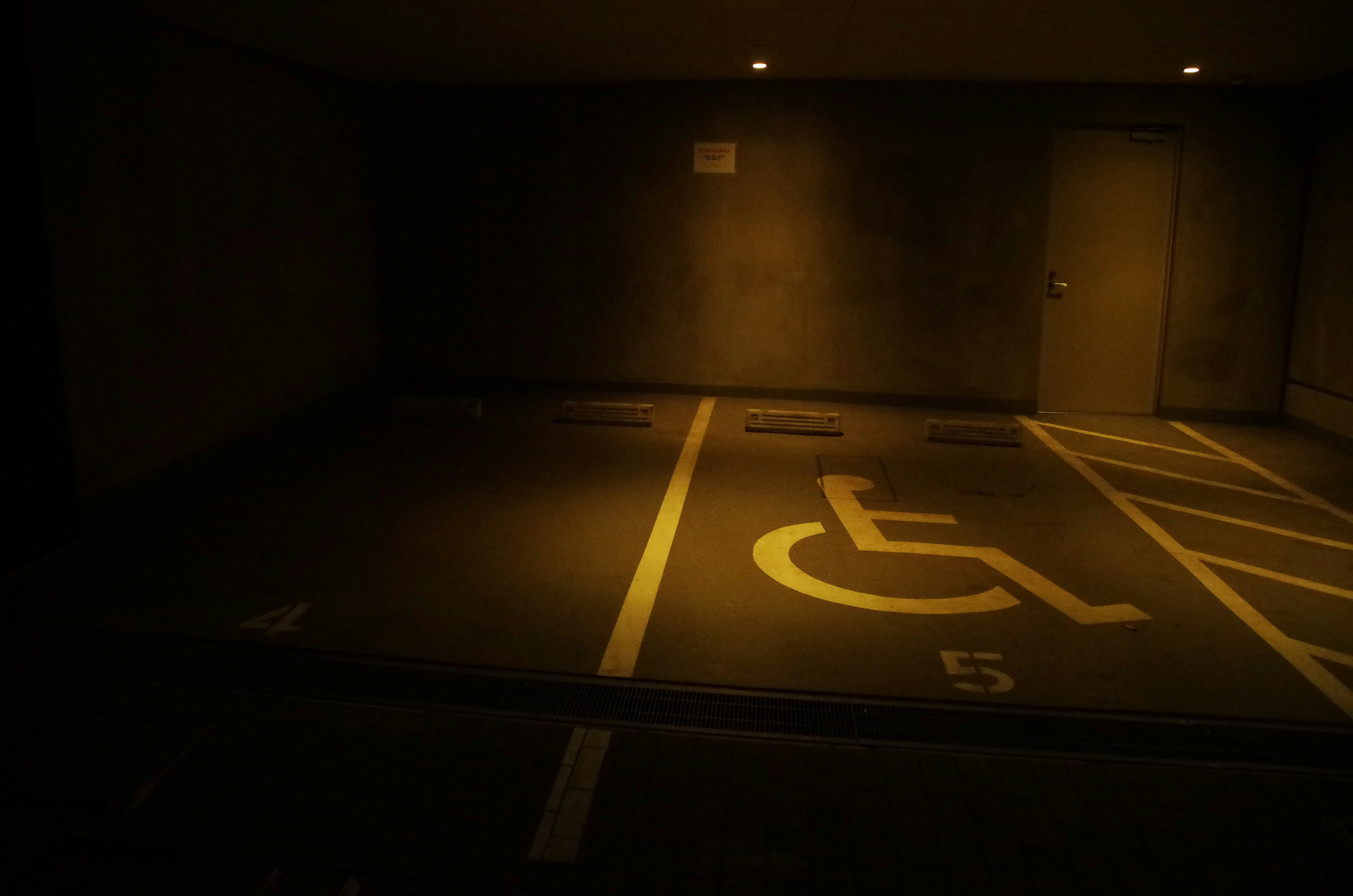 Garasi parkir redup dengan tempat parkir untuk penyandang disabilitas