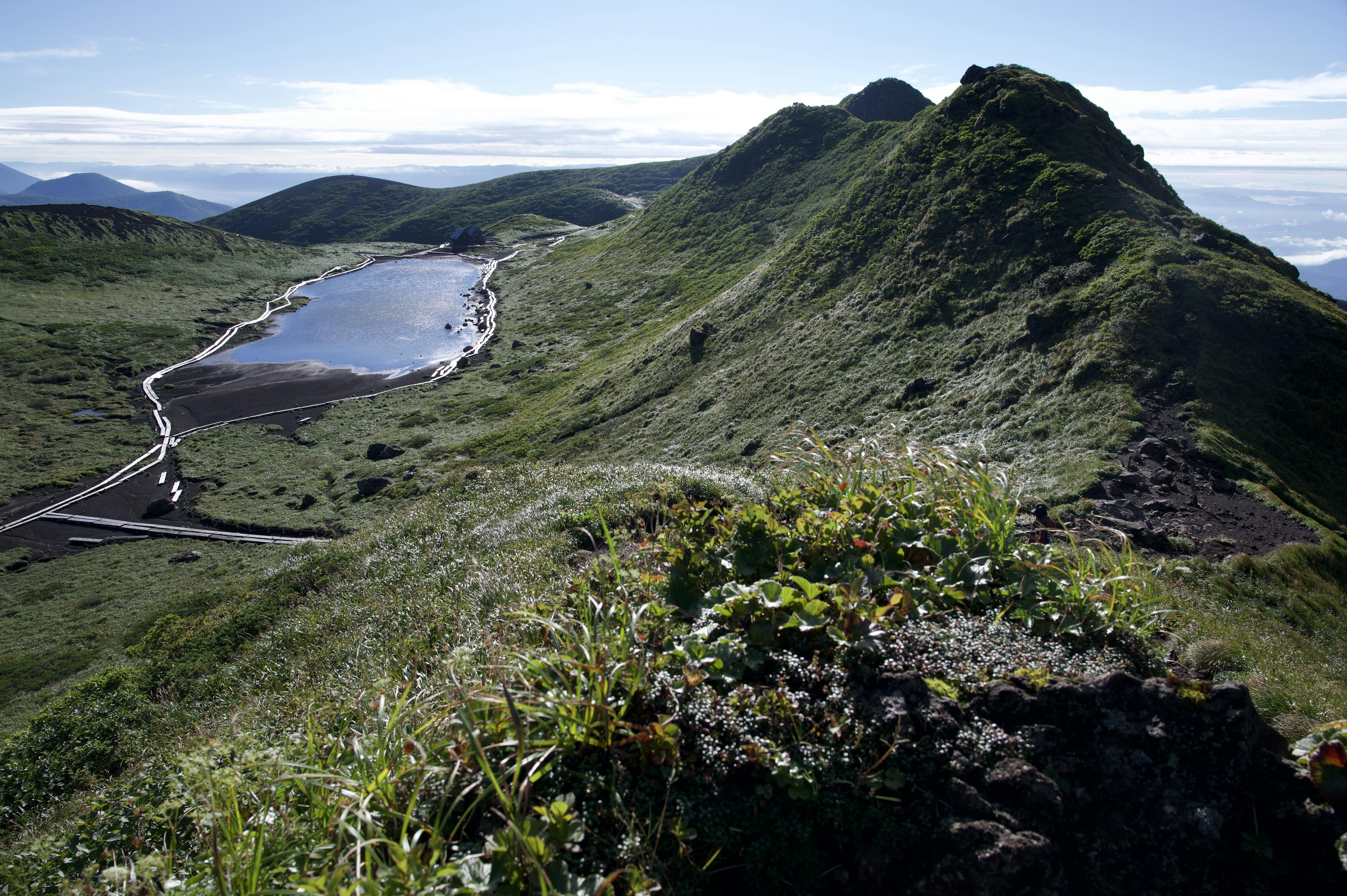 Landschaftsansicht mit grünen Hügeln und einem reflektierenden Gewässer