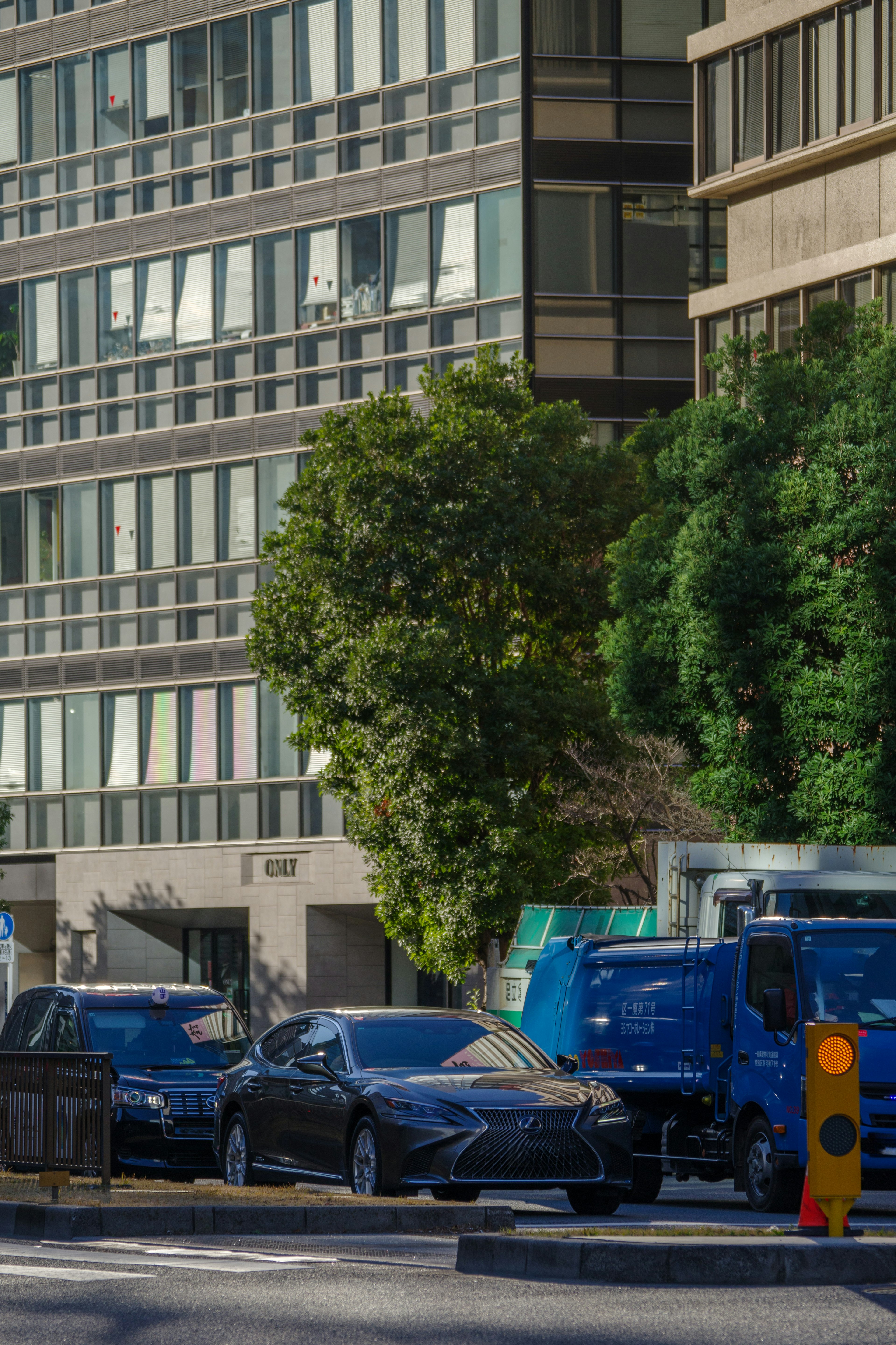 Autos estacionados en una calle urbana con un edificio de gran altura al fondo