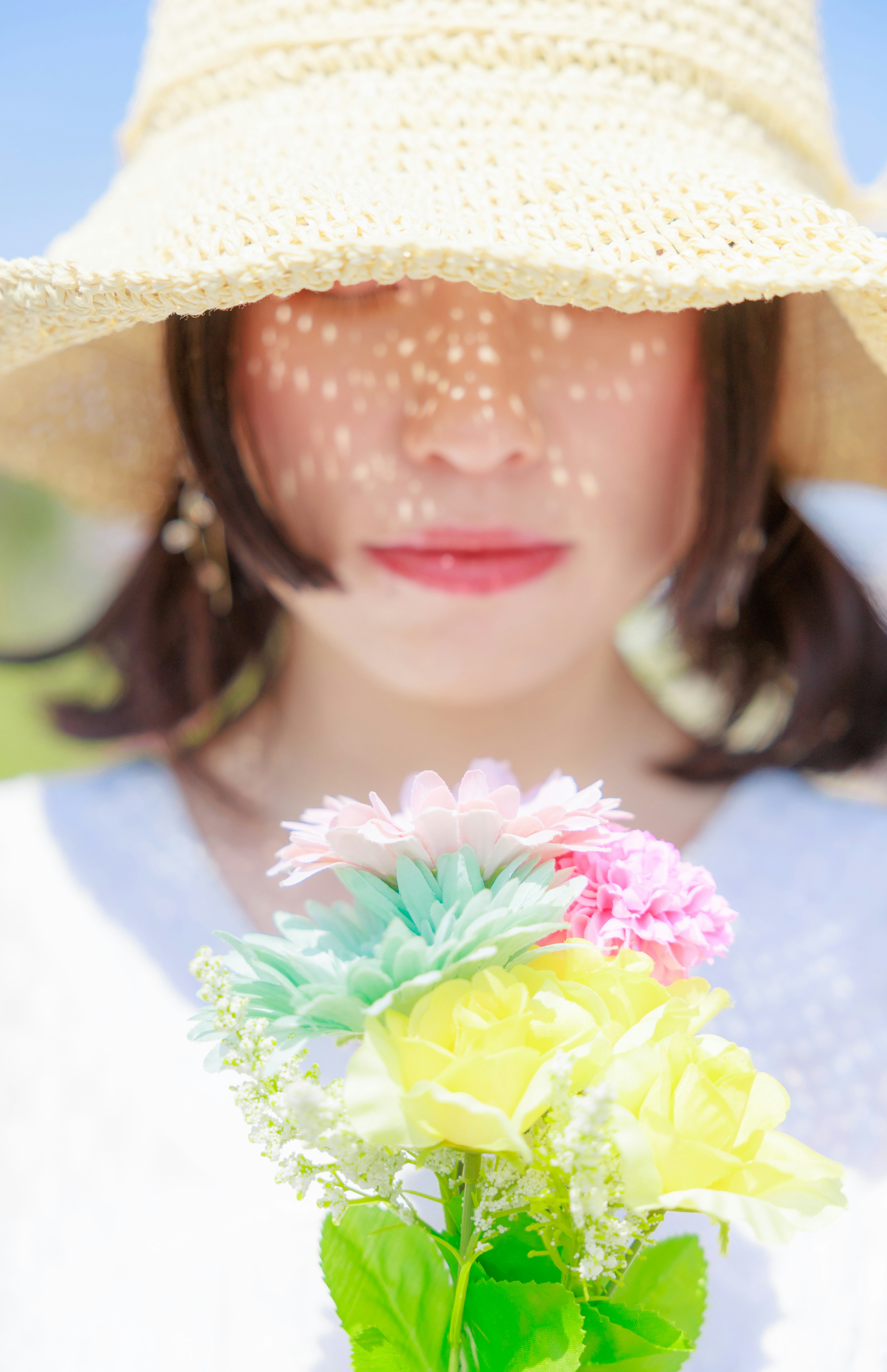 Una donna con un cappello di paglia che tiene un bouquet di fiori colorati