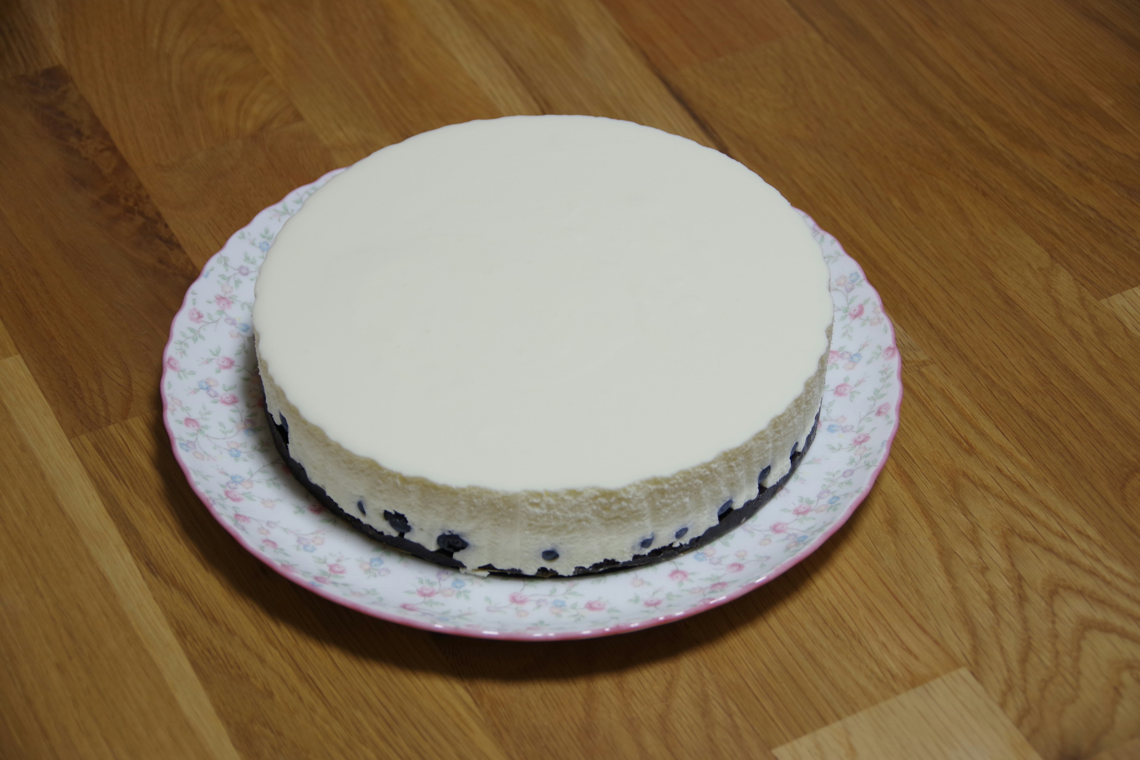 A white cream cake placed on a floral patterned plate