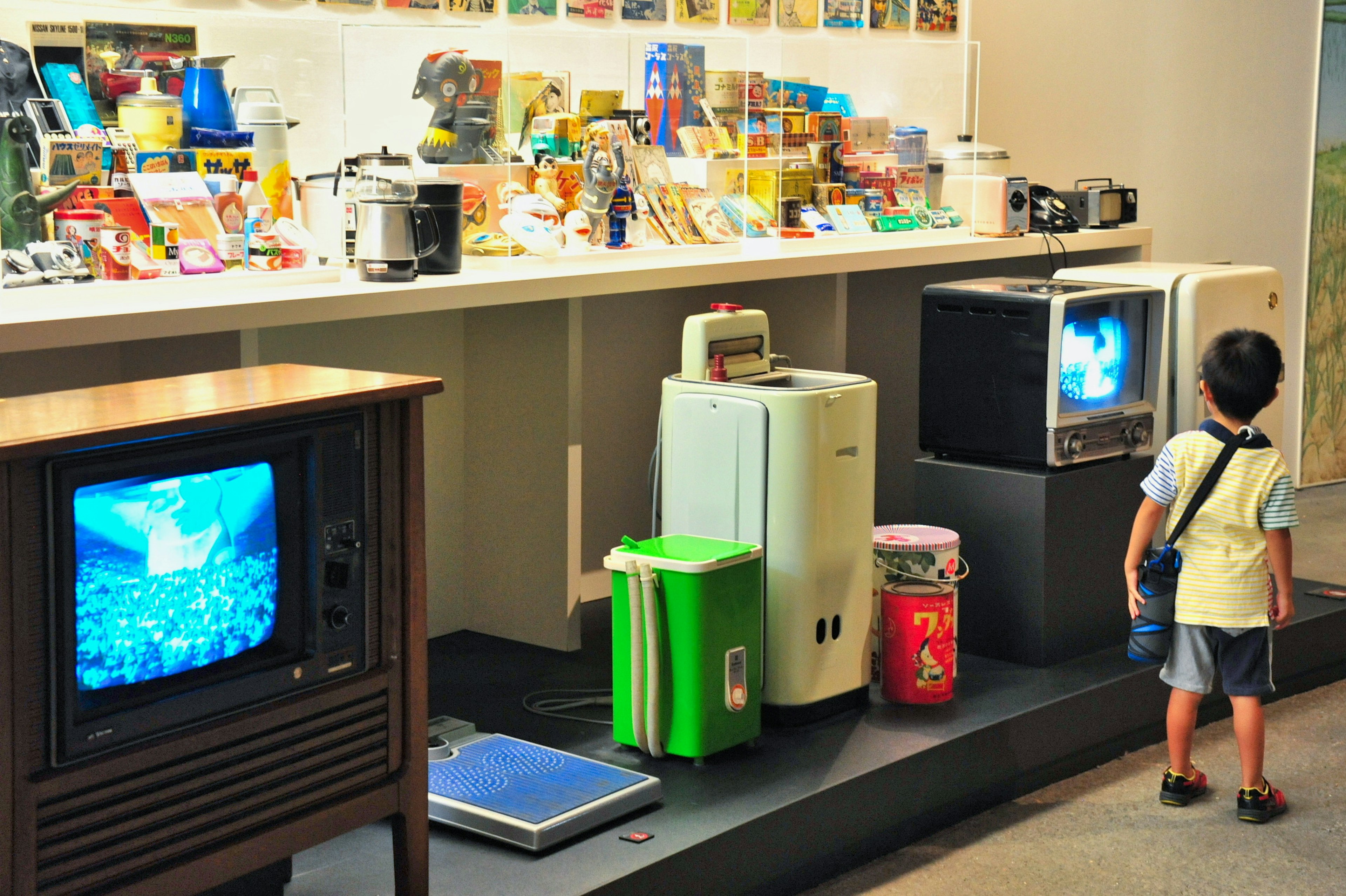 A child observing vintage televisions and appliances in a museum display