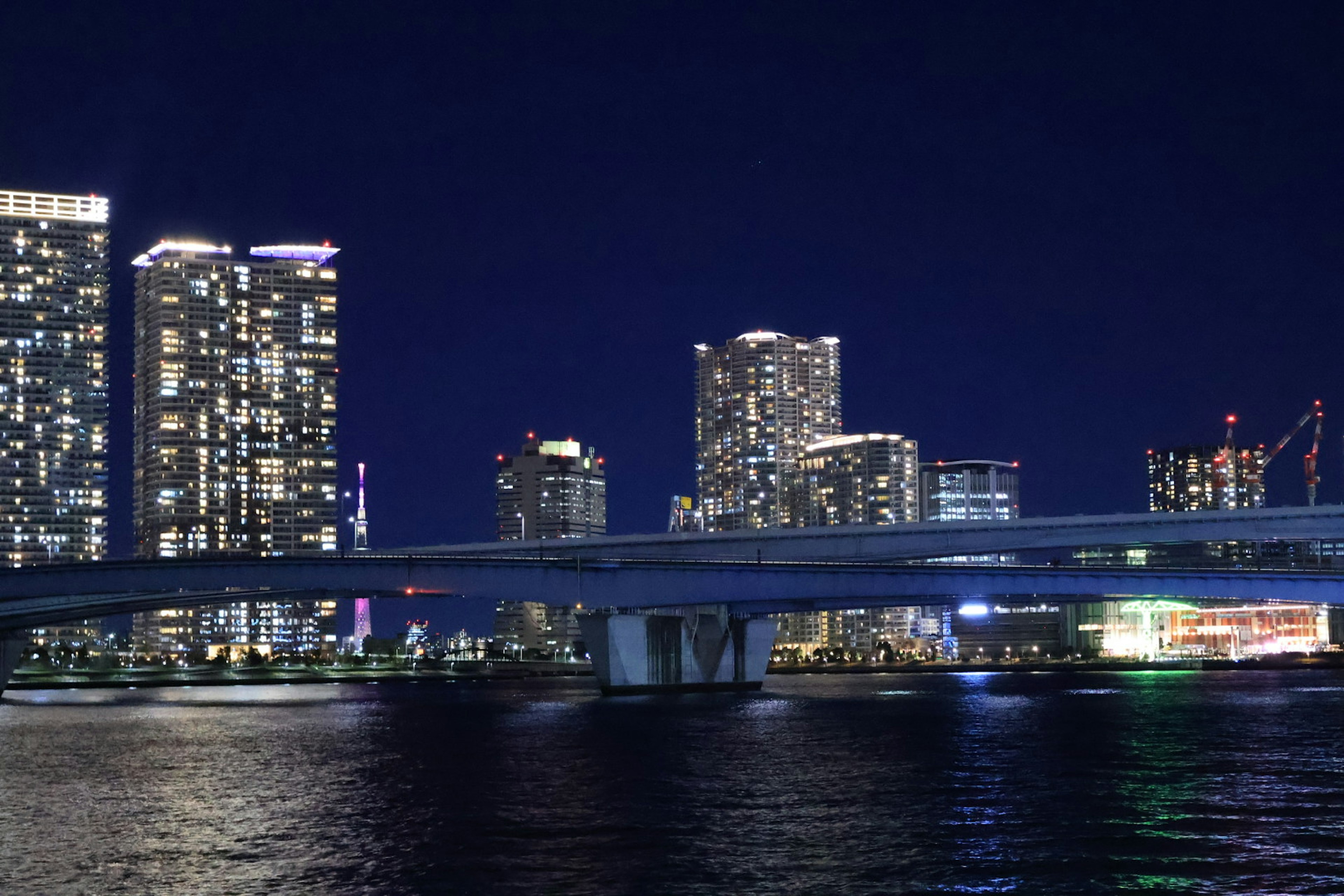 Vista nocturna de rascacielos y un puente reflejos en el agua