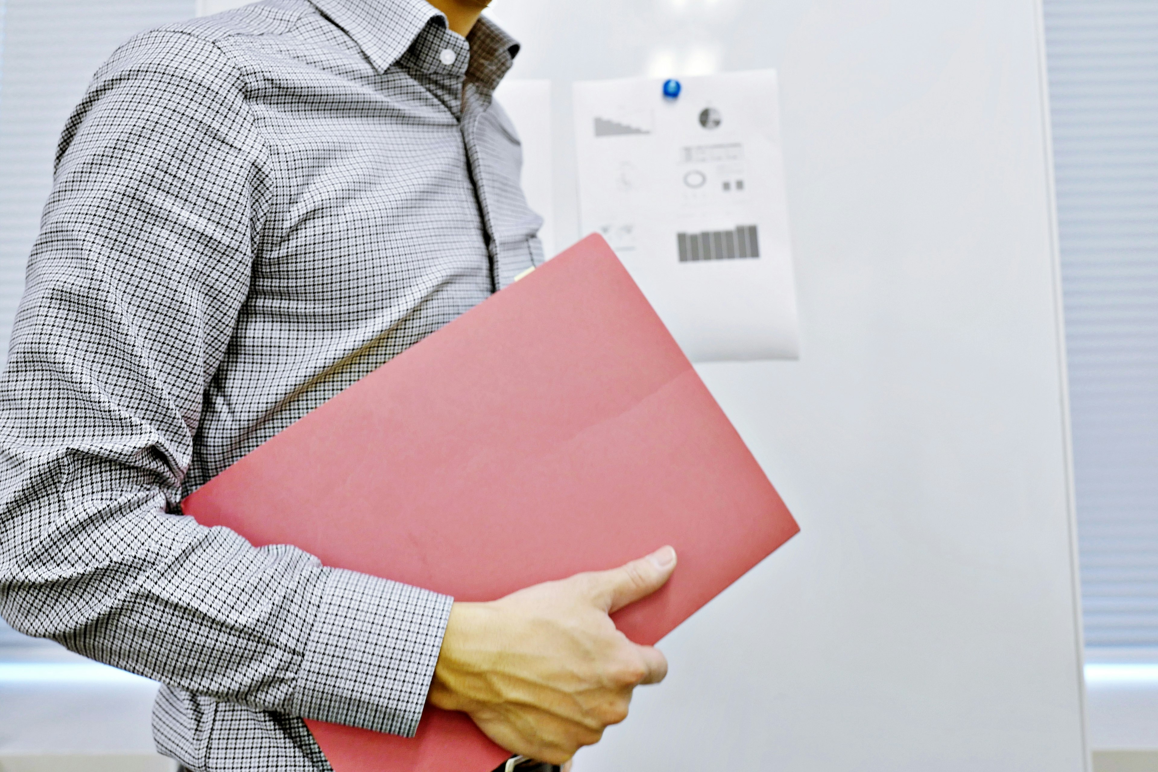 Hombre sosteniendo una carpeta roja en un entorno de negocios