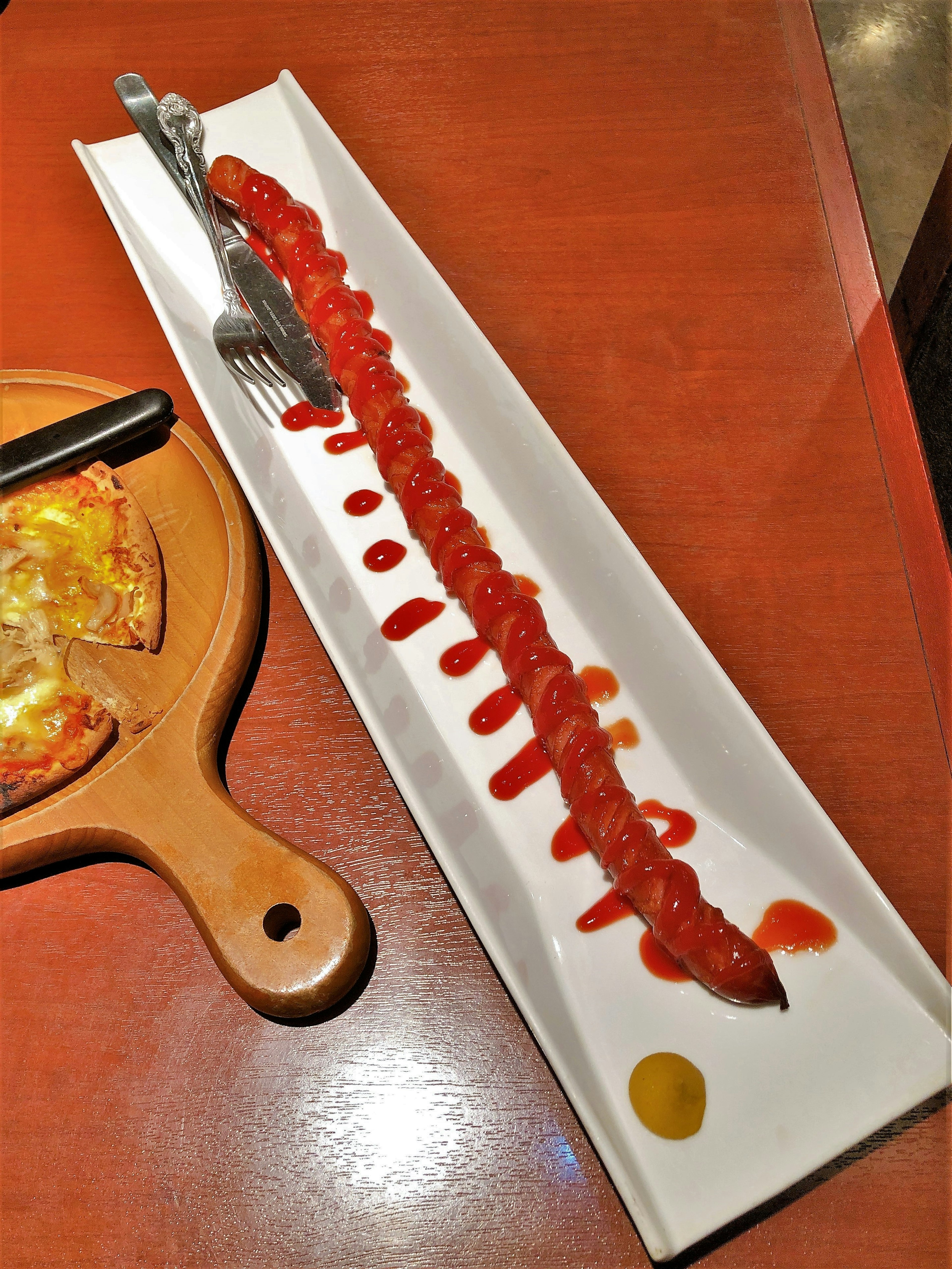 Saucisse longue servie sur une assiette blanche avec du ketchup