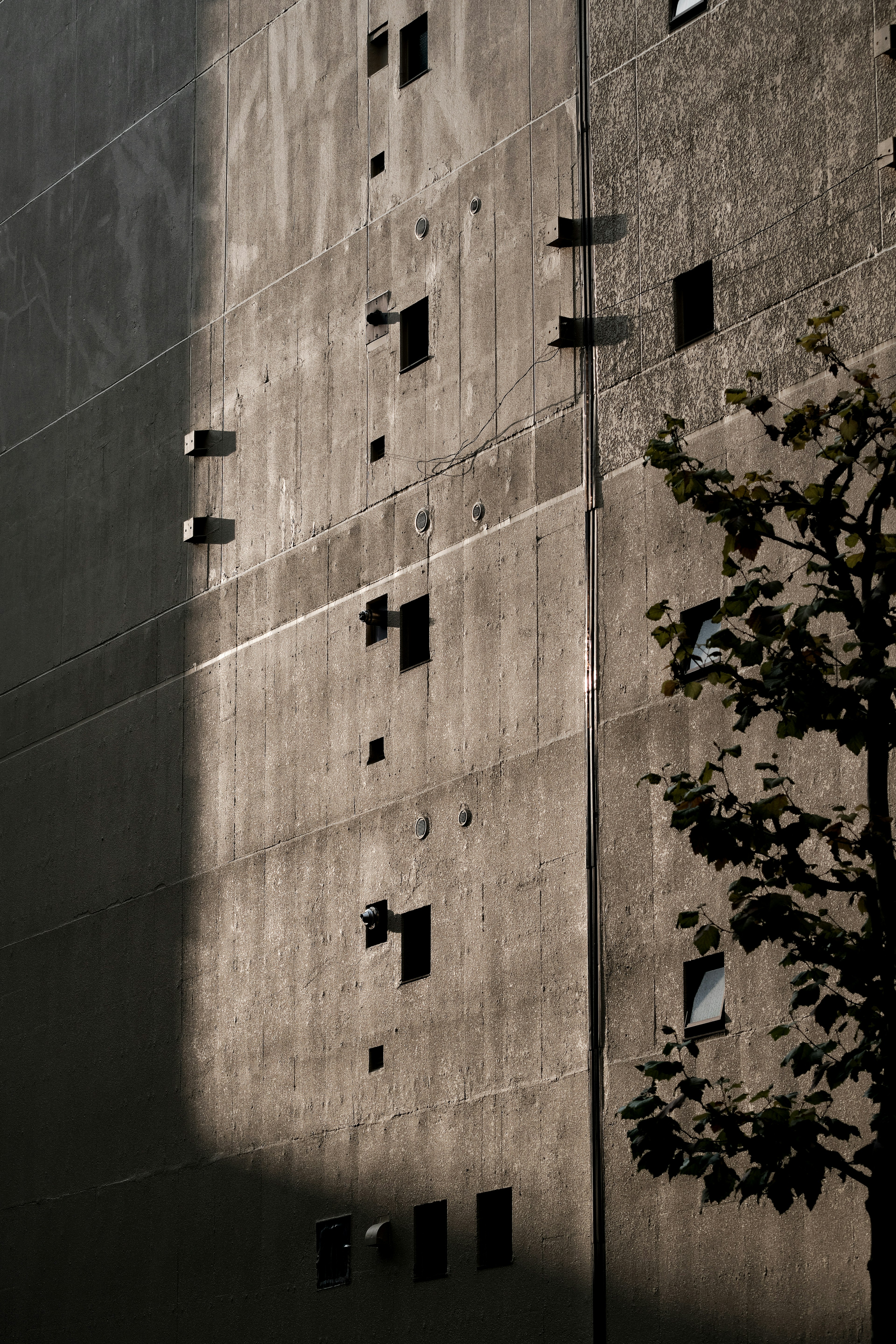 Mur en béton avec des ombres et des ouvertures en forme de fenêtres