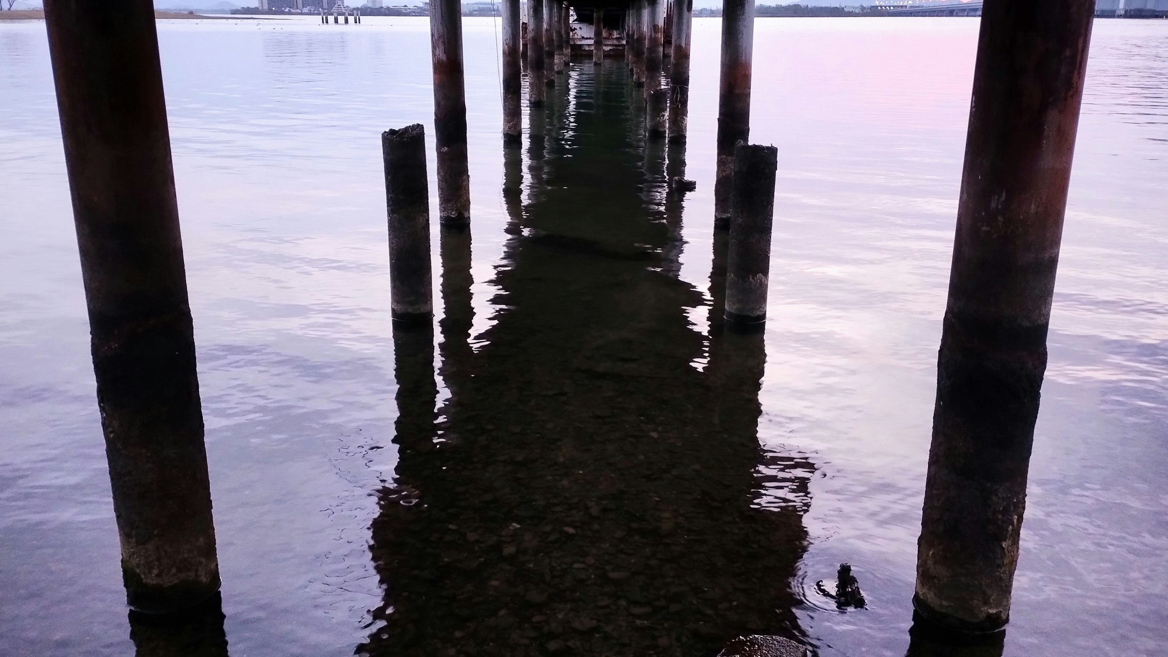 Colonnes de quai reflétées dans l'eau calme avec ambiance sereine